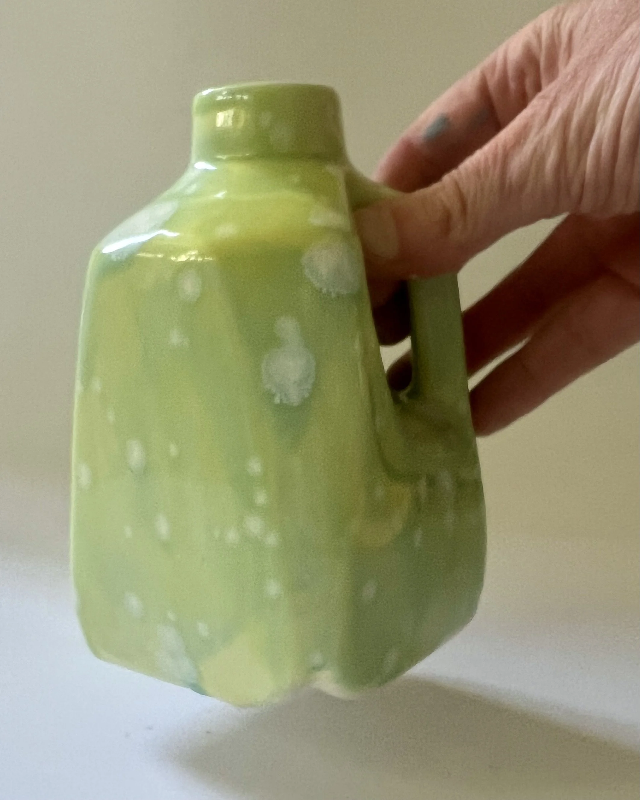 Hand holding porcelain milk jug demonstrating size and proportions.