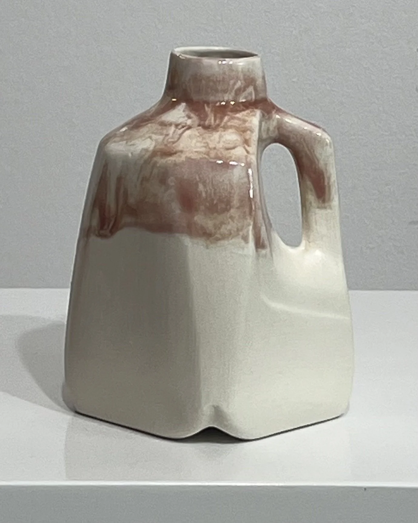 Front view of handmade porcelain jug with creamy white body and plum glaze