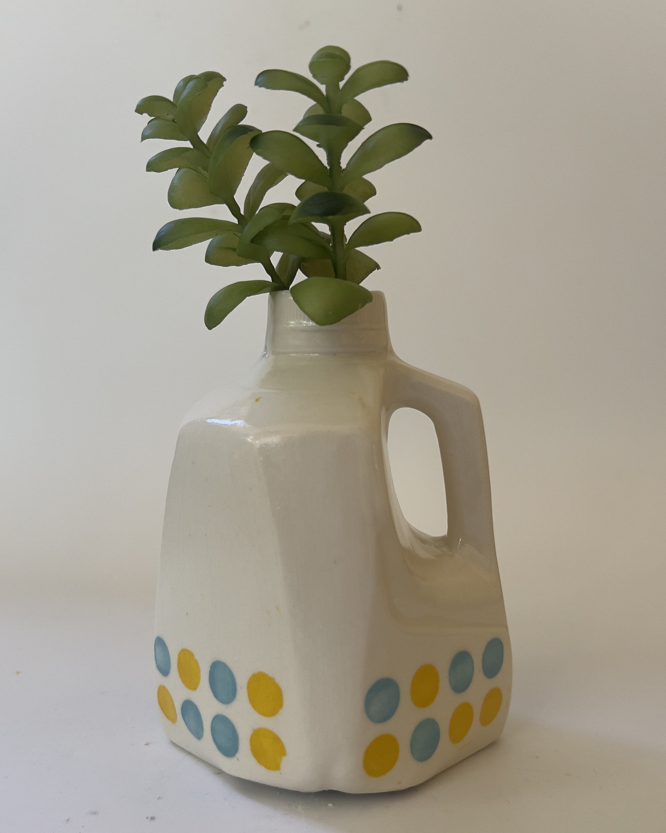 White ceramic jug sculpture styled with green plant stem