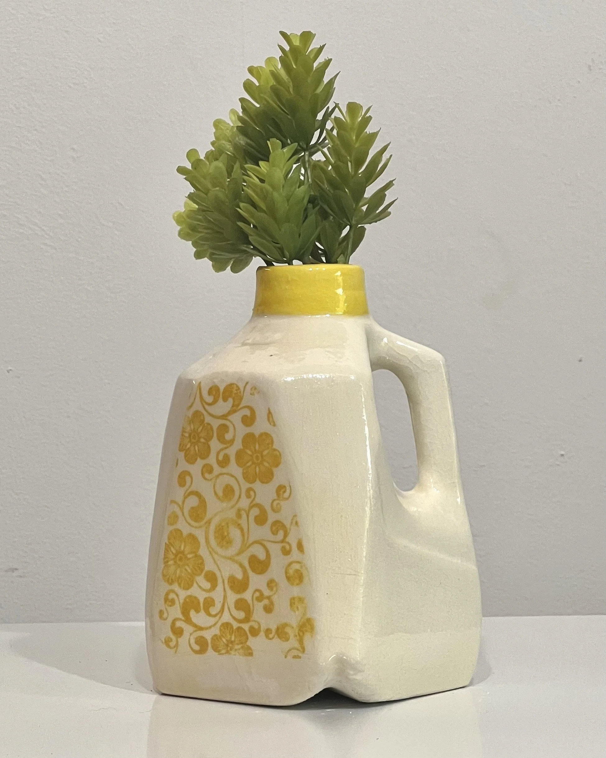 Yellow floral porcelain milk jug with vintage-inspired floral transfer holding fresh greenery.