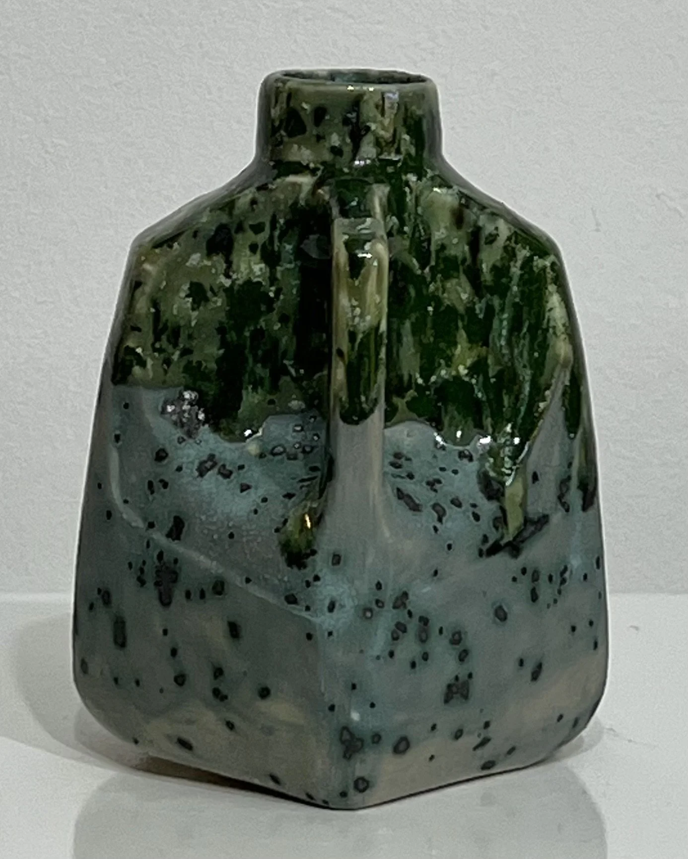 Right-side view of handmade ceramic milk jug with dark green glaze and angular handle