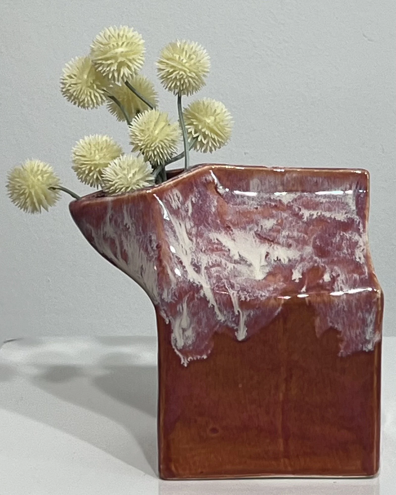 Handbuilt ceramic milk carton vase with dried flowers, finished in layered Chun Plum and Light Flux glazes.