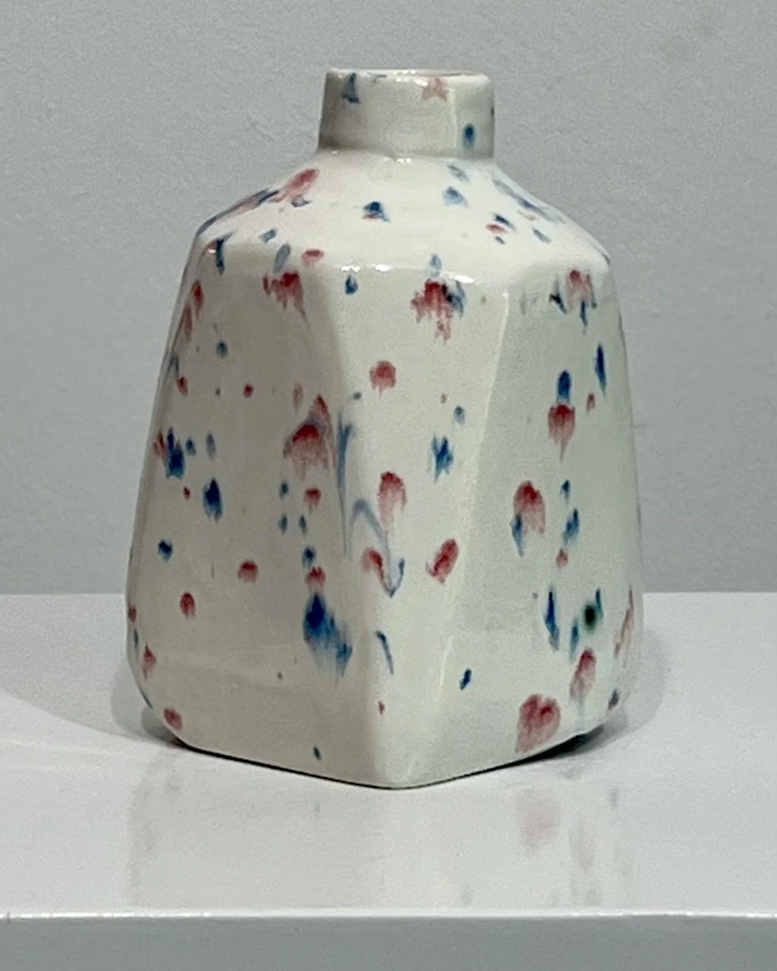 Back view of handmade porcelain milk jug vase with colorful splatter glaze and sculptural milk jug form.