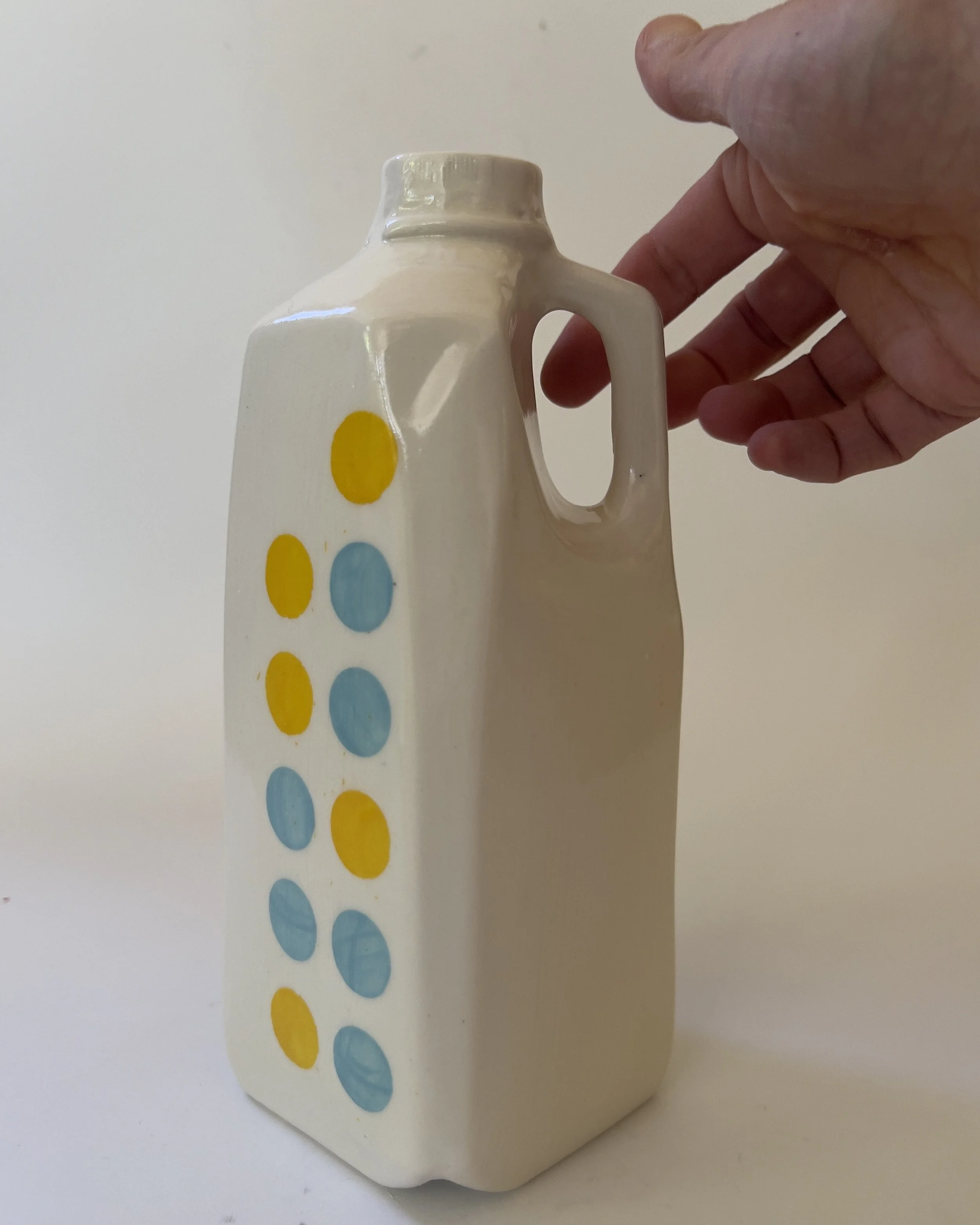 Handmade ceramic tall jug shown in hand for scale