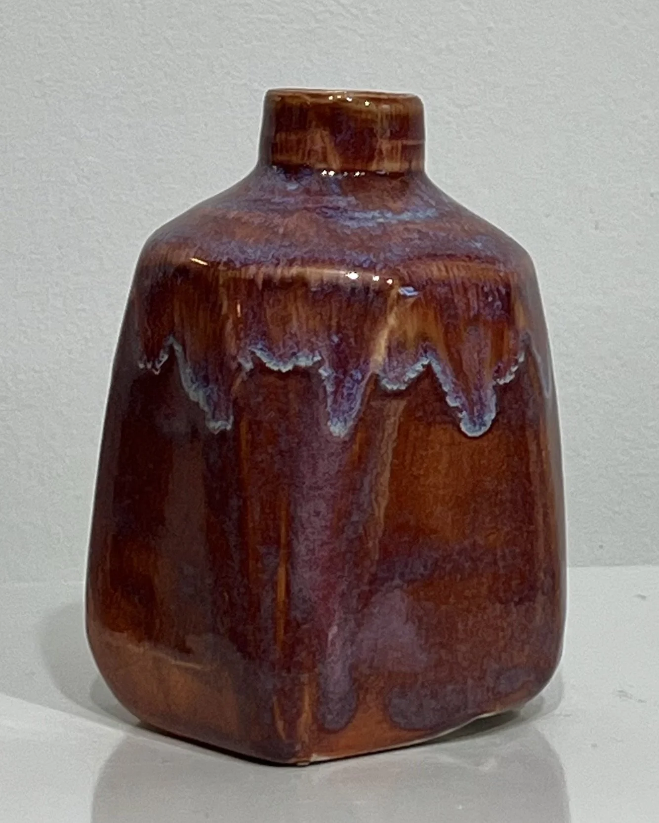 Side view of one-of-a-kind red-brown ceramic milk jug with pale glaze accents