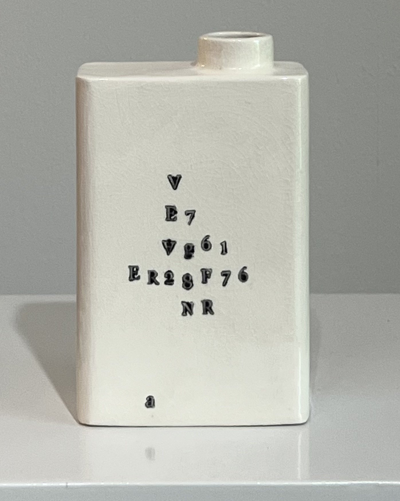 Rear view of a contemporary porcelain milk carton showing impressed typography and glossy white glaze.