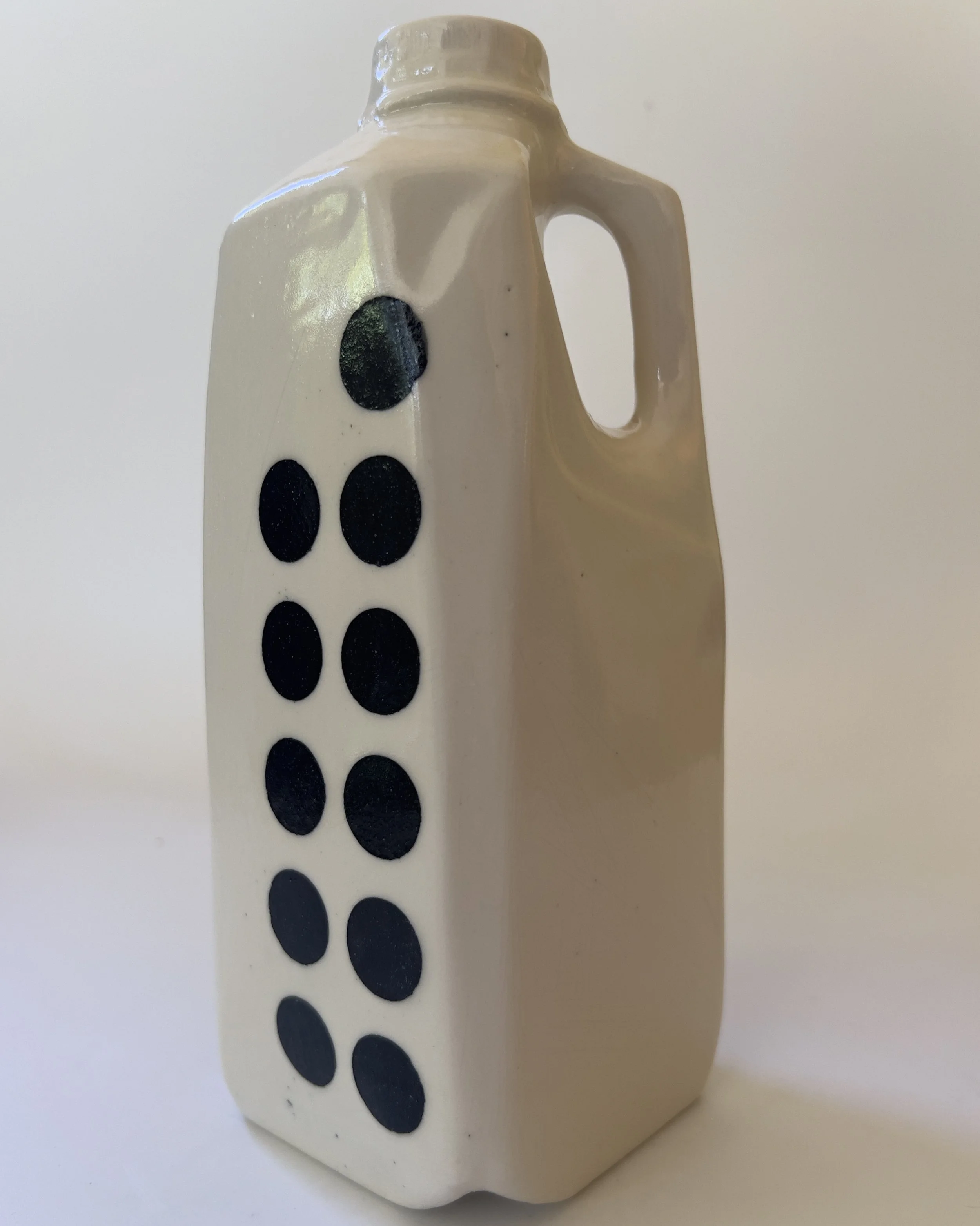 Front view of handmade ceramic jug vase with black dot pattern and iridescent white glaze