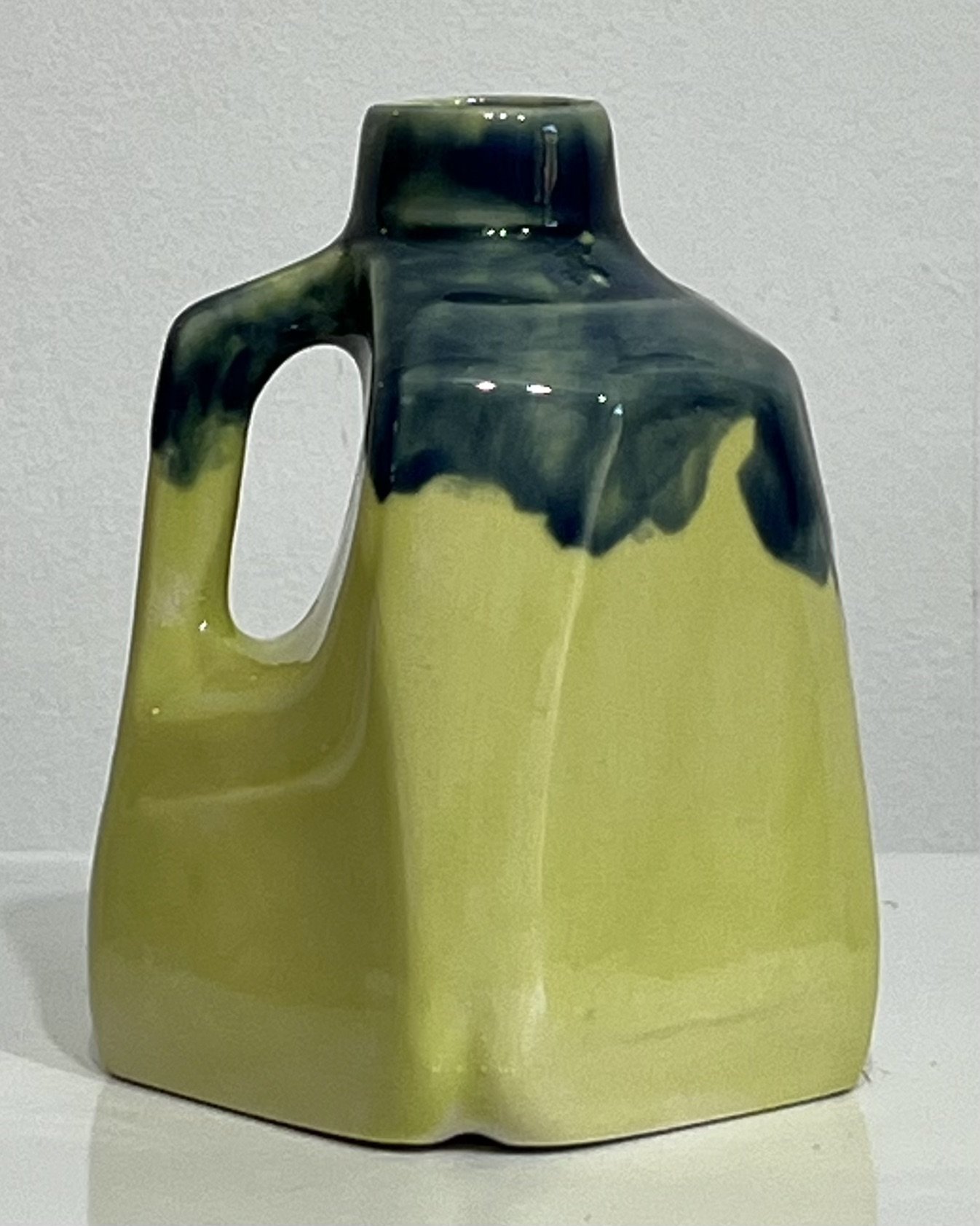 Back view of one-of-a-kind porcelain milk jug with glossy dark blue drips over yellow-green glaze