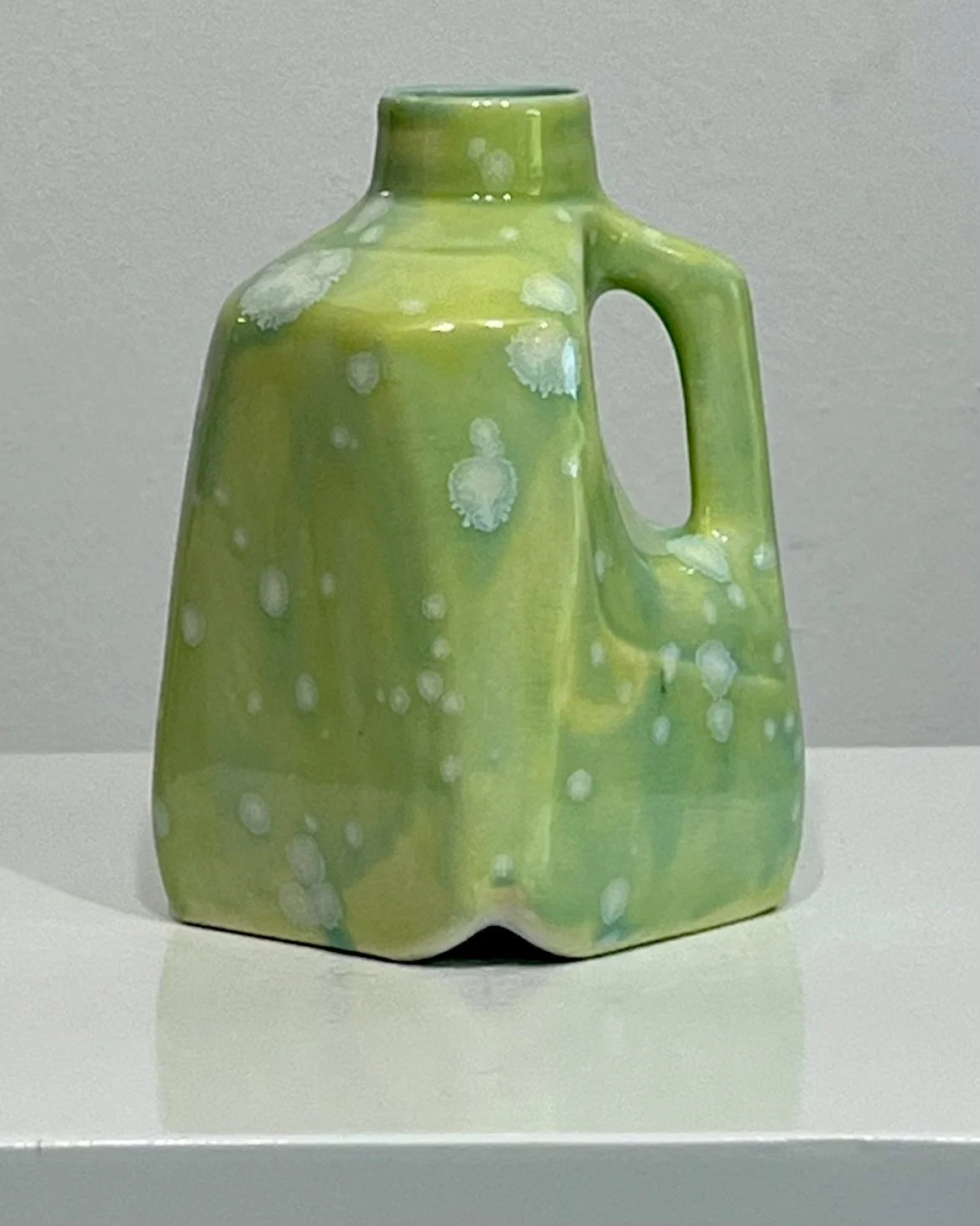 Front view of porcelain milk jug 26.58 glazed in Celadon Bloom over Pear with crystalline white blooms.