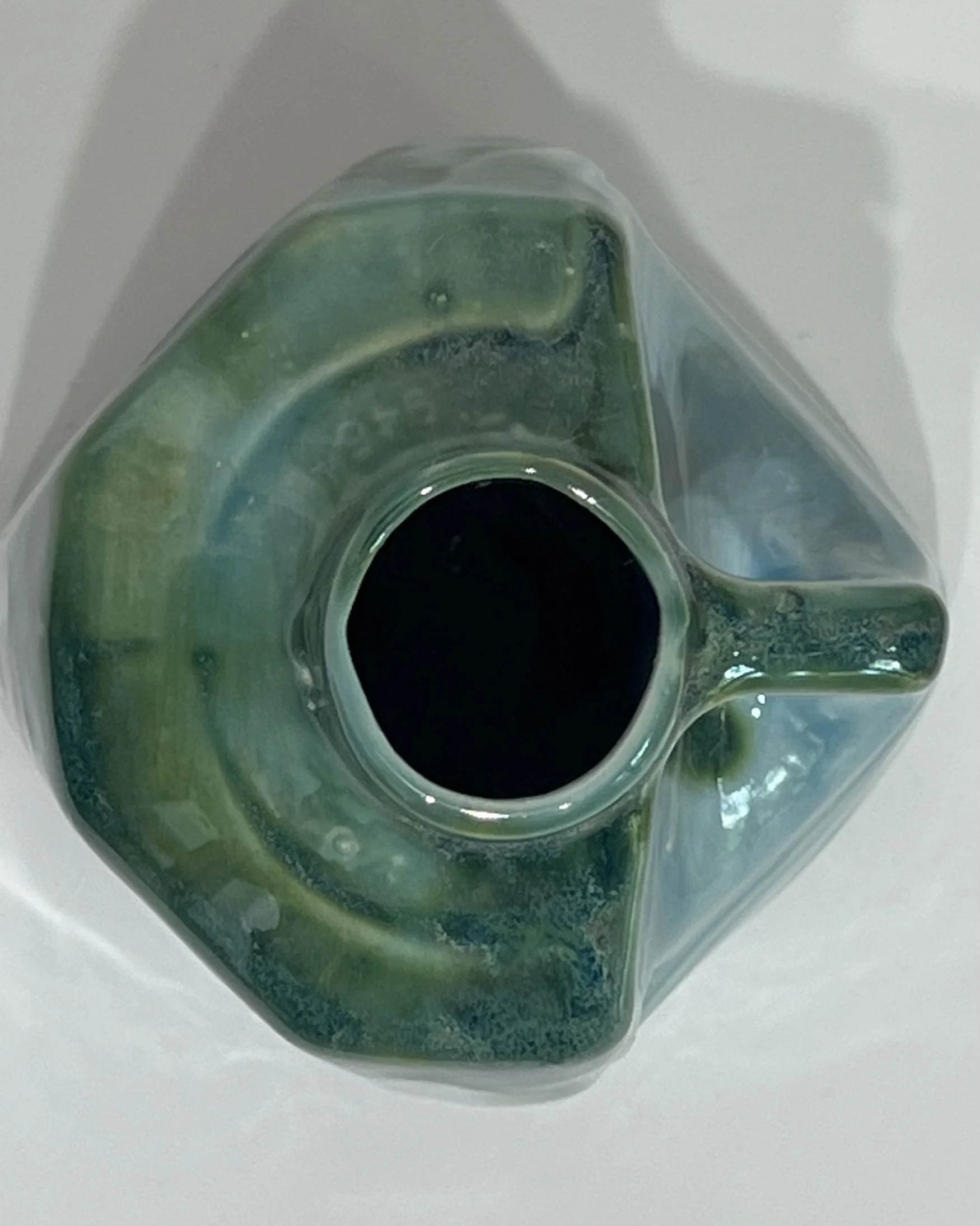 Top view of ceramic milk jug sculpture showing the opening and layered green and blue-green glaze around the rim.
