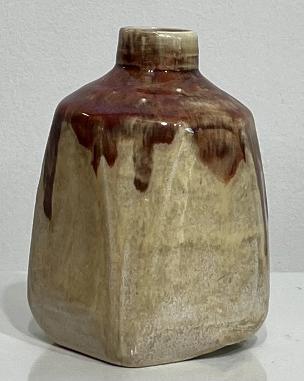 Side view of cream ceramic milk jug showing integrated handle and glaze variations