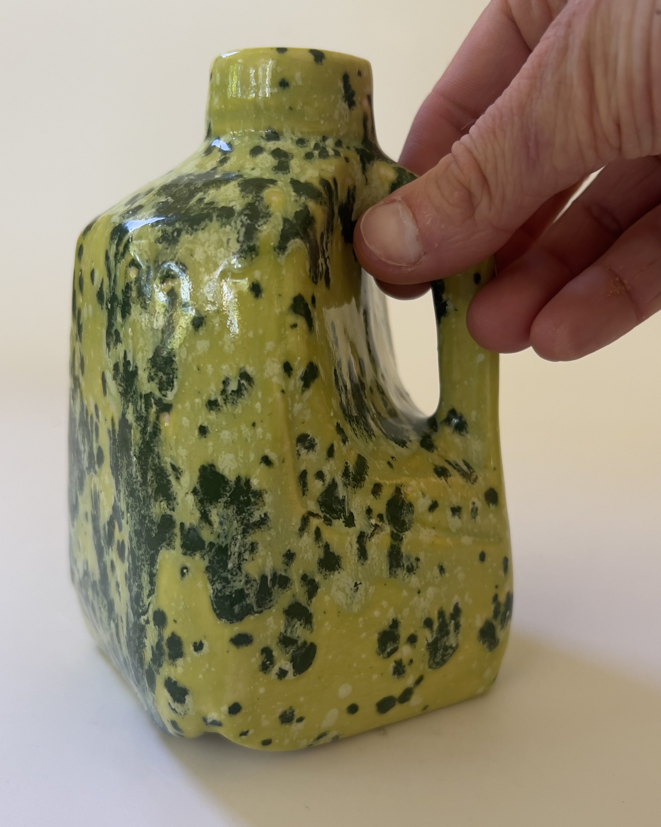 Hand holding small sculptural ceramic jug for scale reference