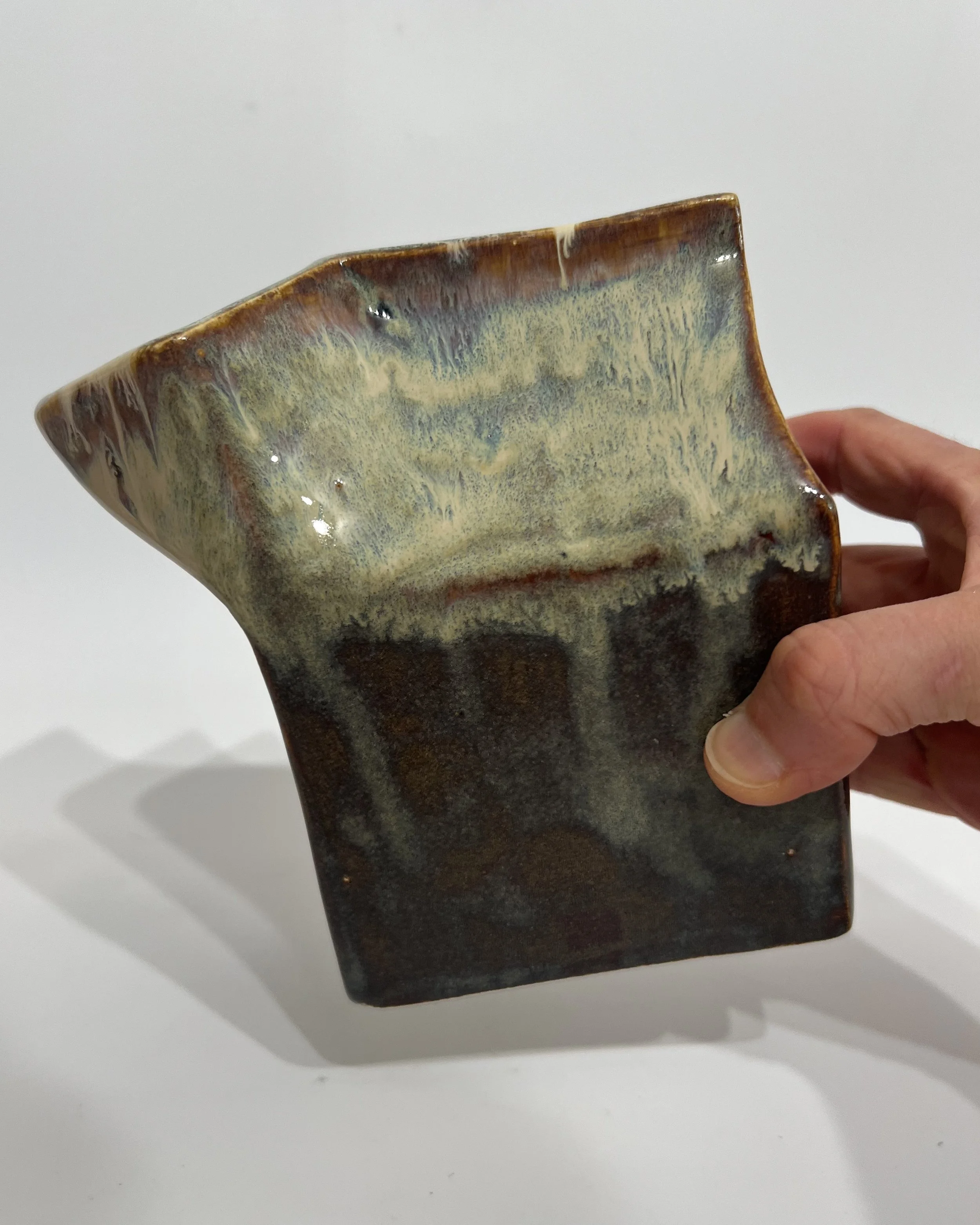 Handmade ceramic milk carton vase held in hand for scale