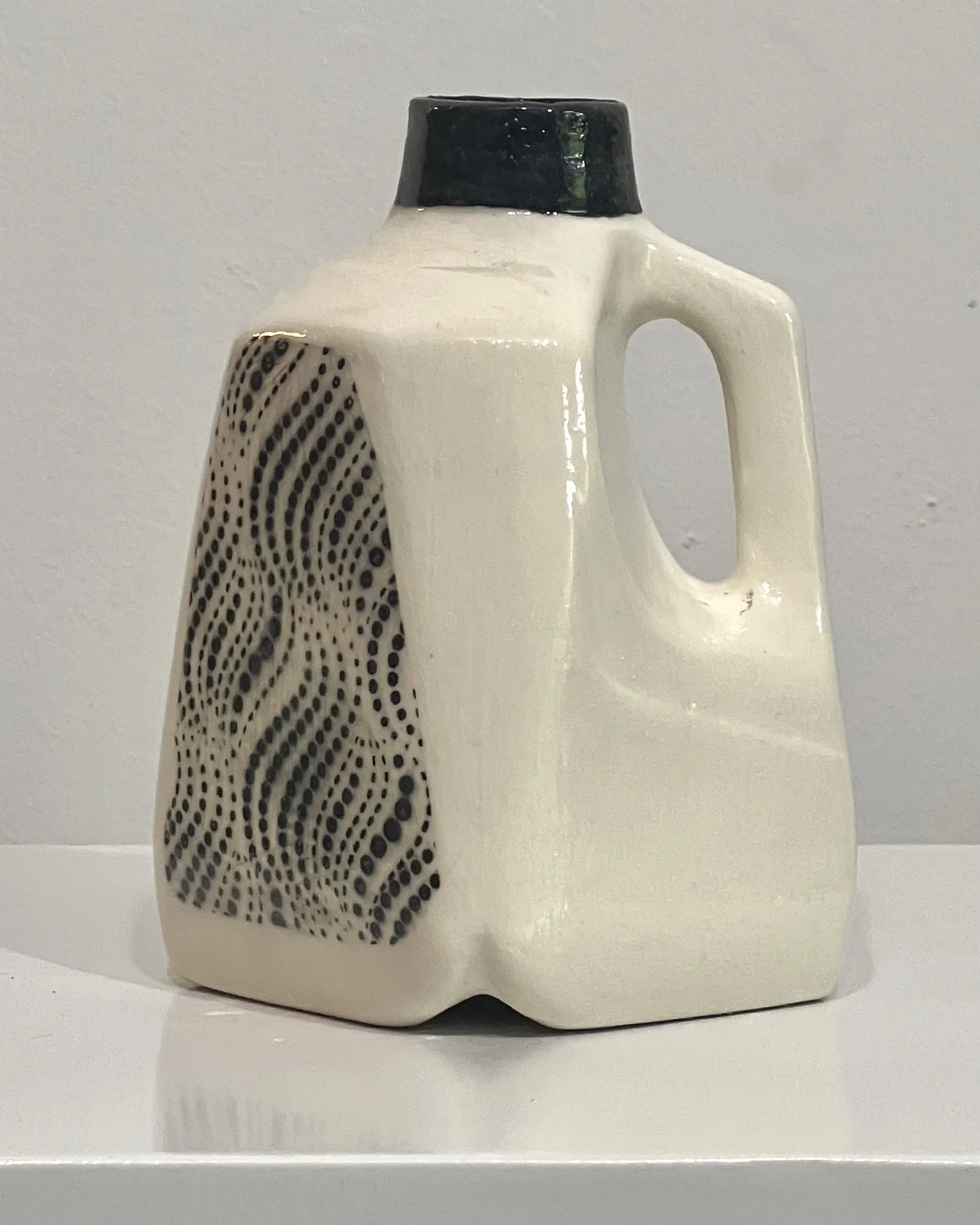 Close view of black dotted wave motif on porcelain milk jug vase.