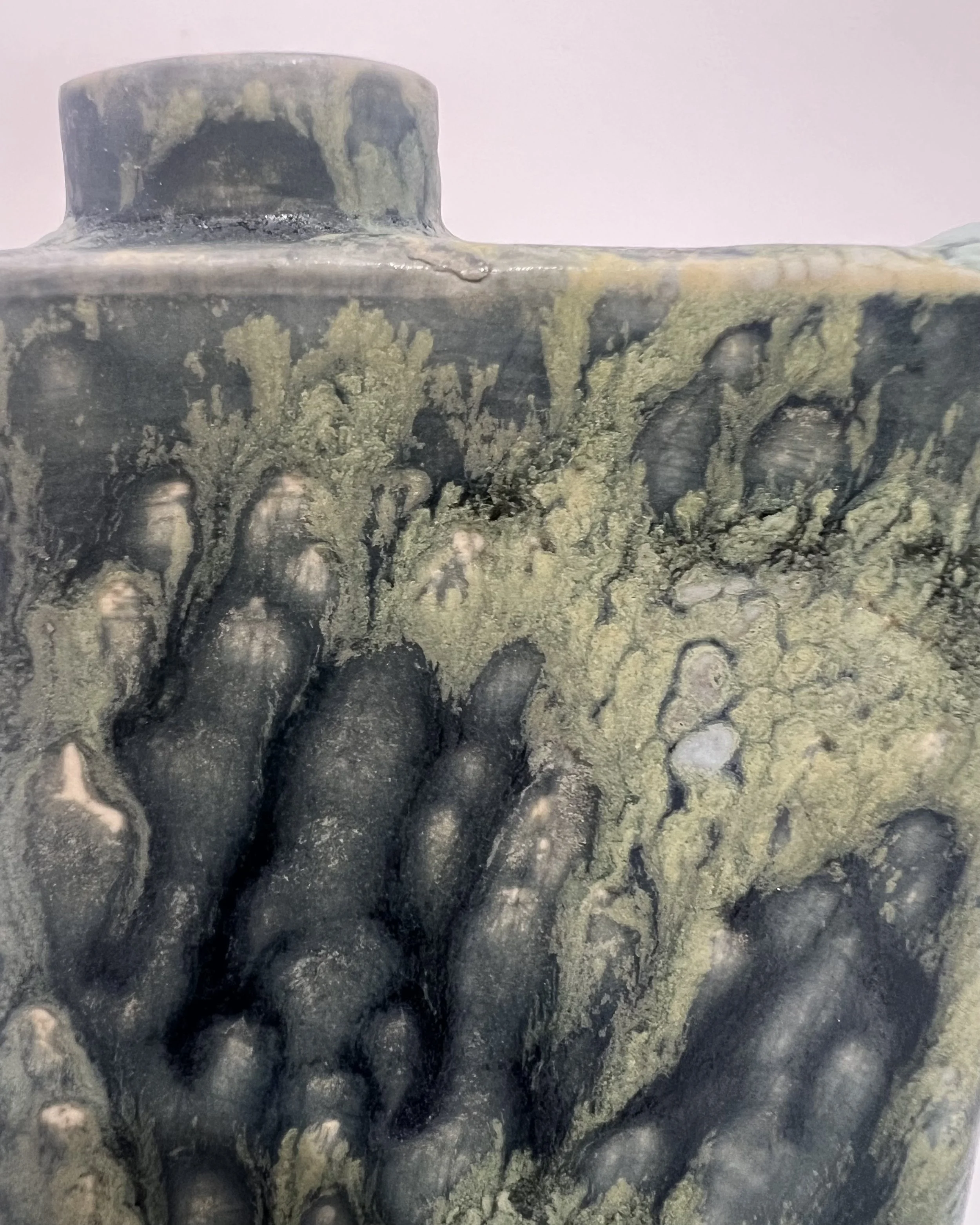 Close-up of Satin Oribe and Mudcrack glazes revealing textured blue-green and earthy surface patterns.