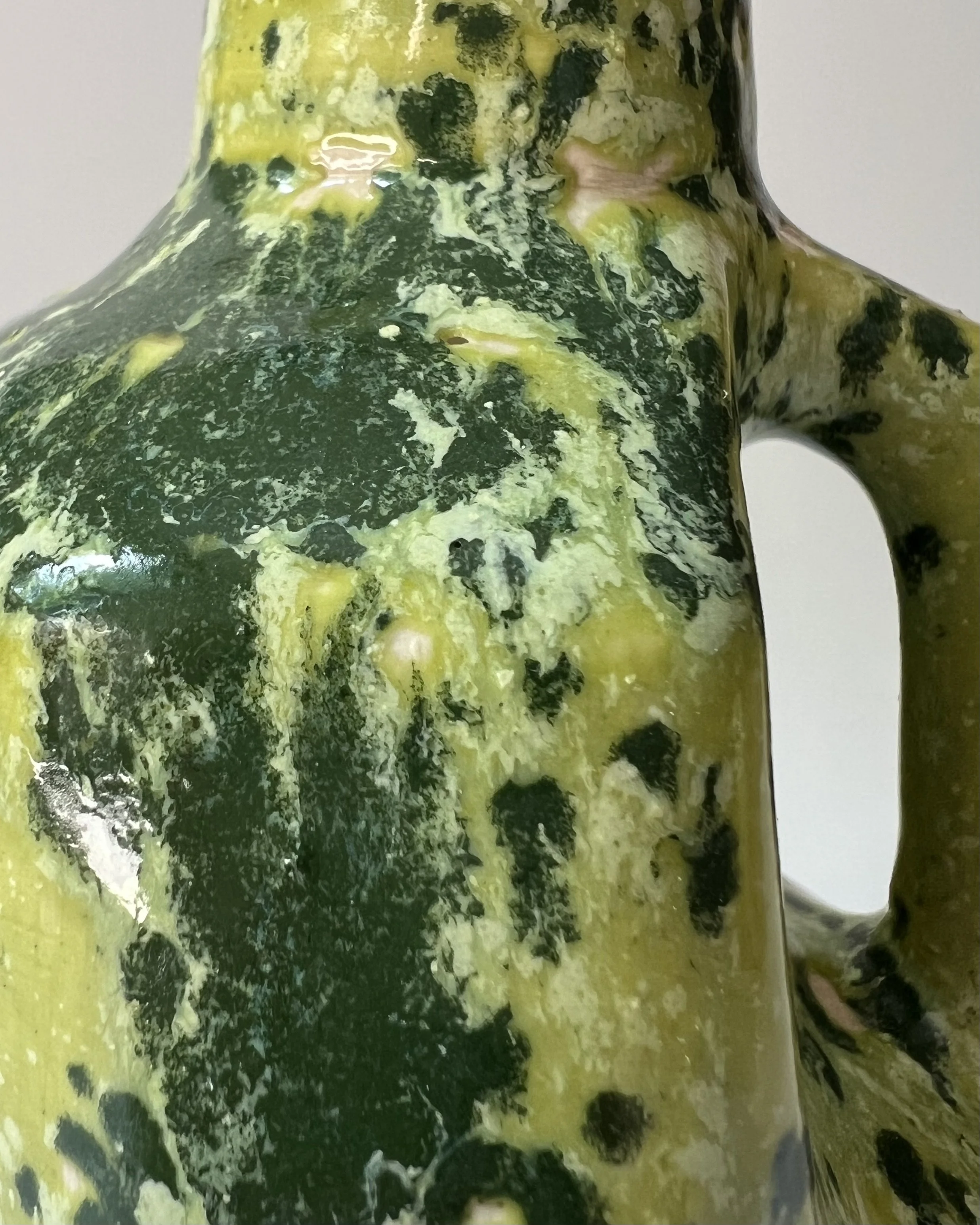 Close-up of the textured green speckled glaze on a handmade porcelain milk jug.