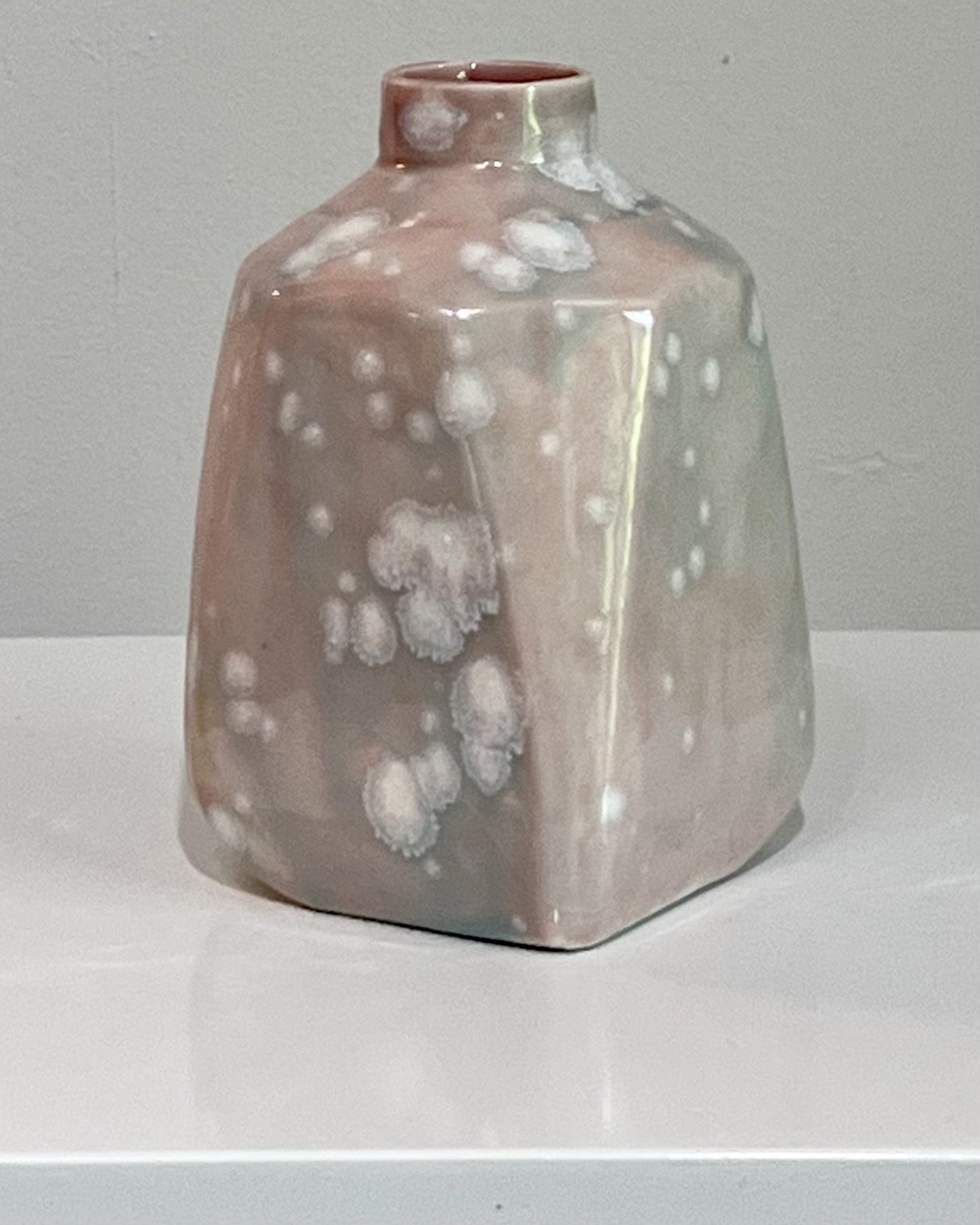Three-quarter front view of handmade porcelain milk jug finished in Celadon Bloom over Cherry Blossom glaze.