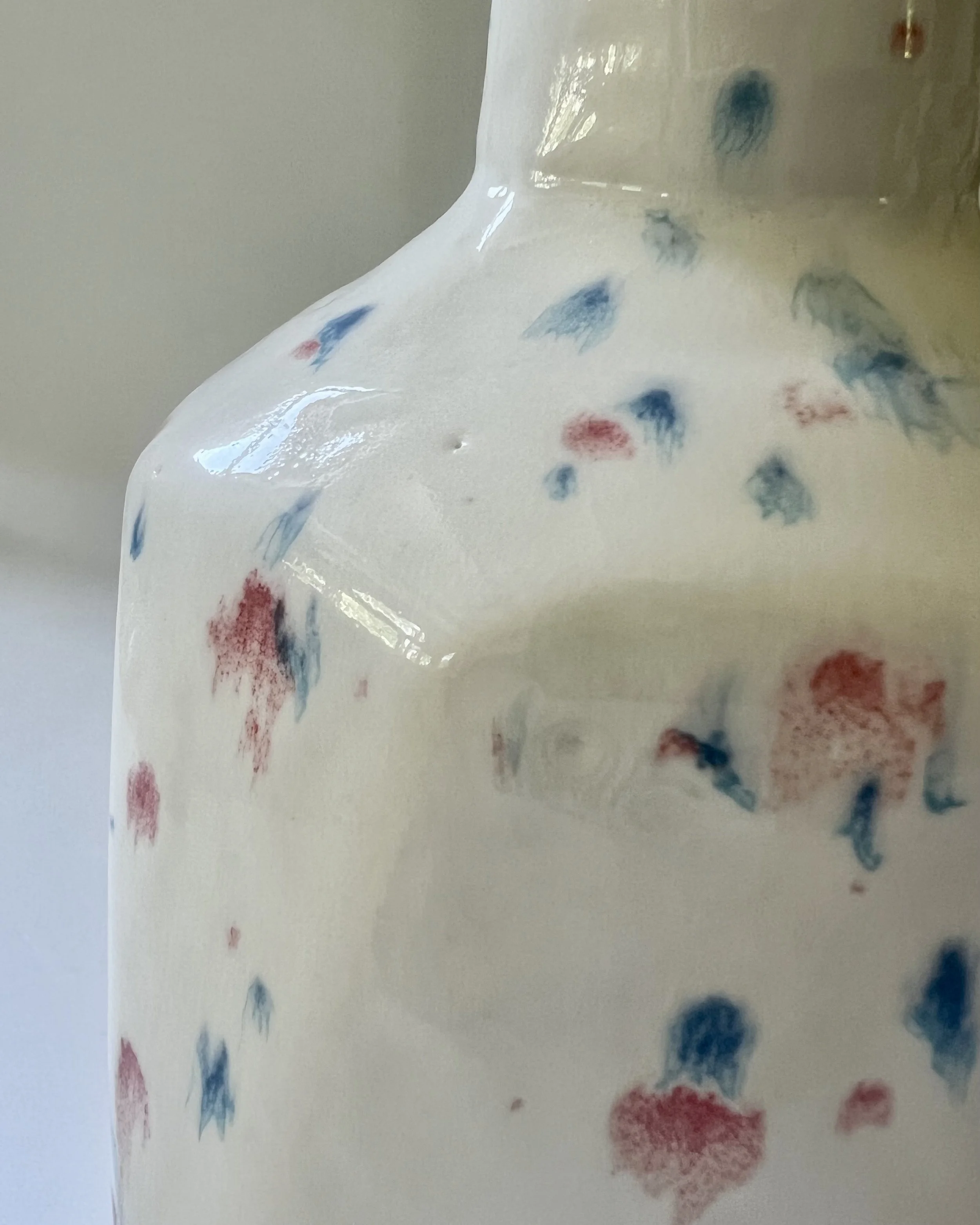 Close-up of surface texture and colorful splatter glaze on handmade porcelain ceramic vase.