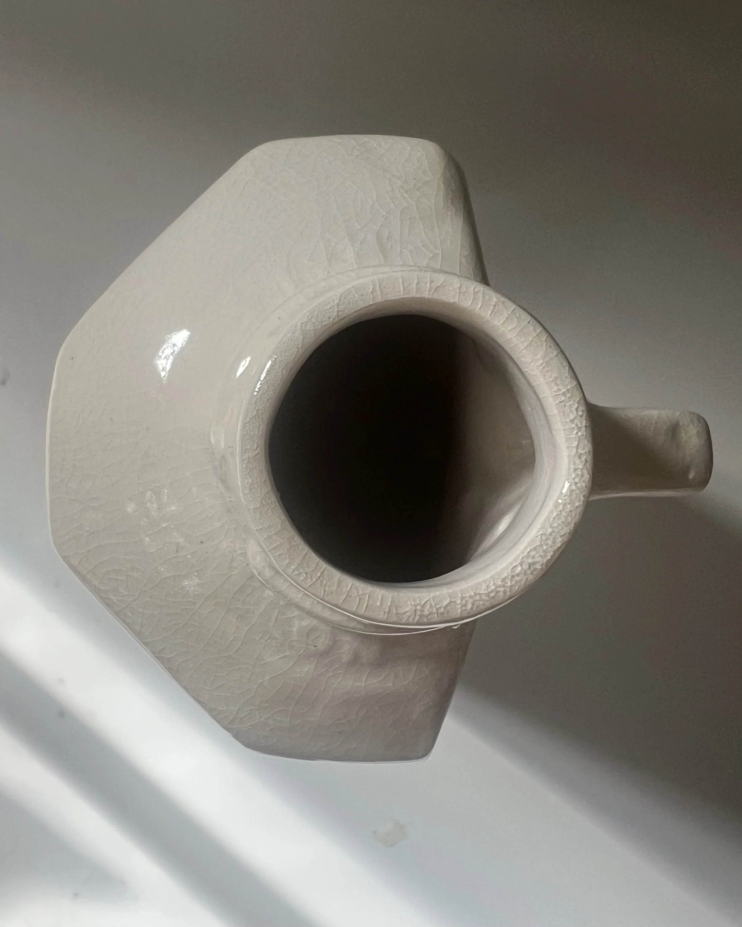 Top view of the opening of a handbuilt tall porcelain milk jug with glossy glazed interior.