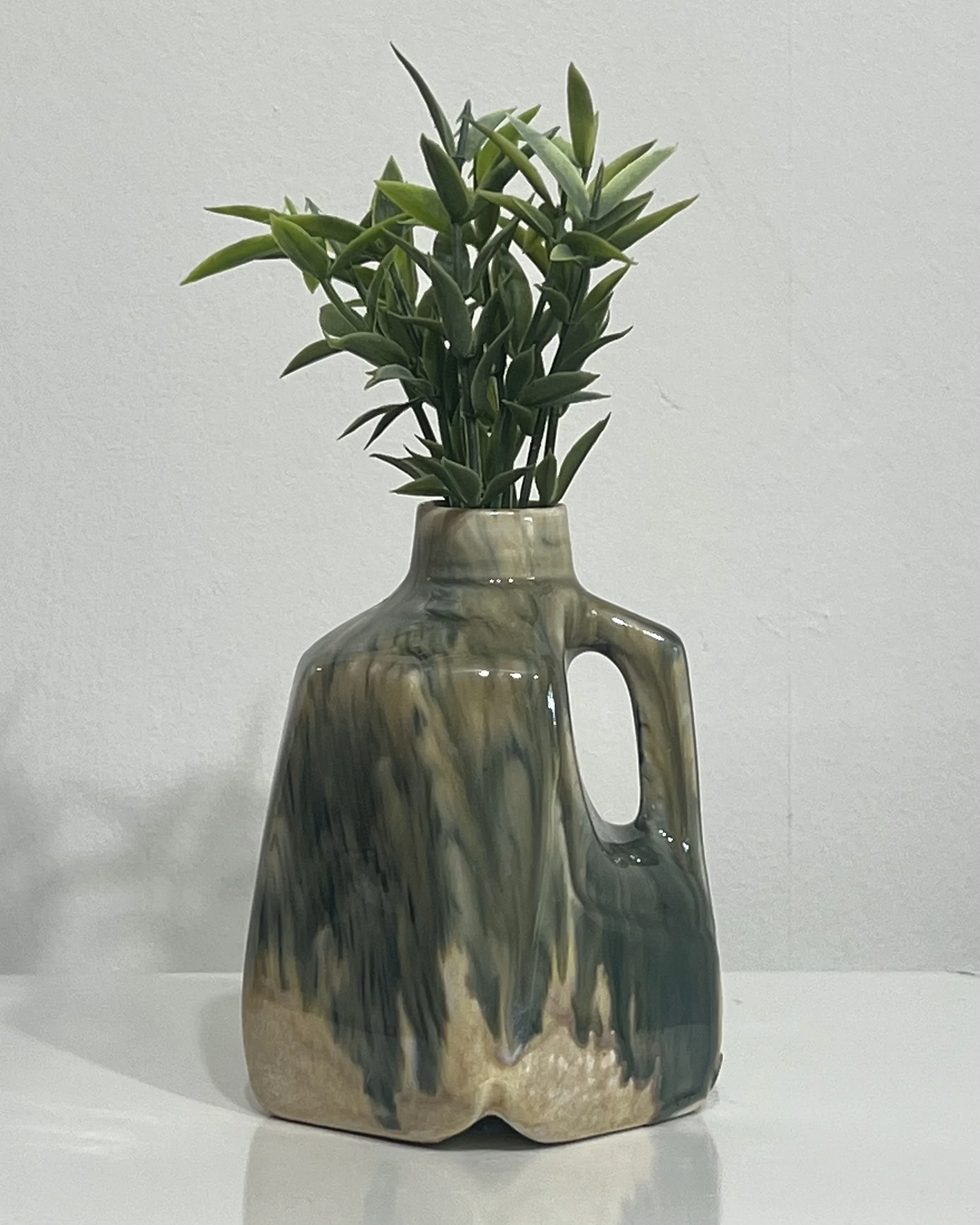 Handmade porcelain milk jug vase by Alissa Van Atta featuring Oatmeal and Bloomin' Blue glazes in layered blue-green, olive, and cream tones, displayed with greenery.
