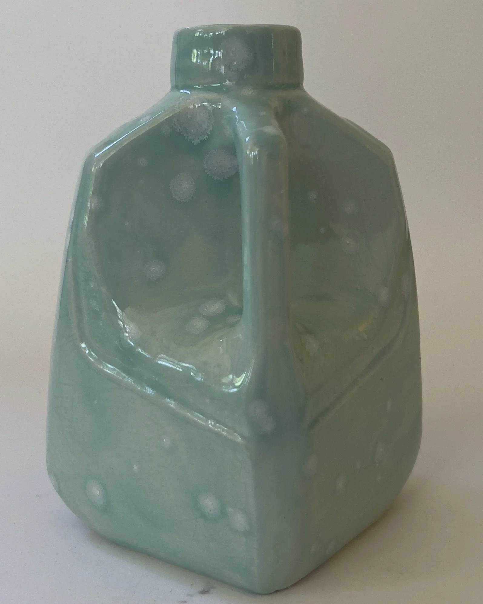 Celadon bloom glazed ceramic milk jug sculpture viewed from side angle