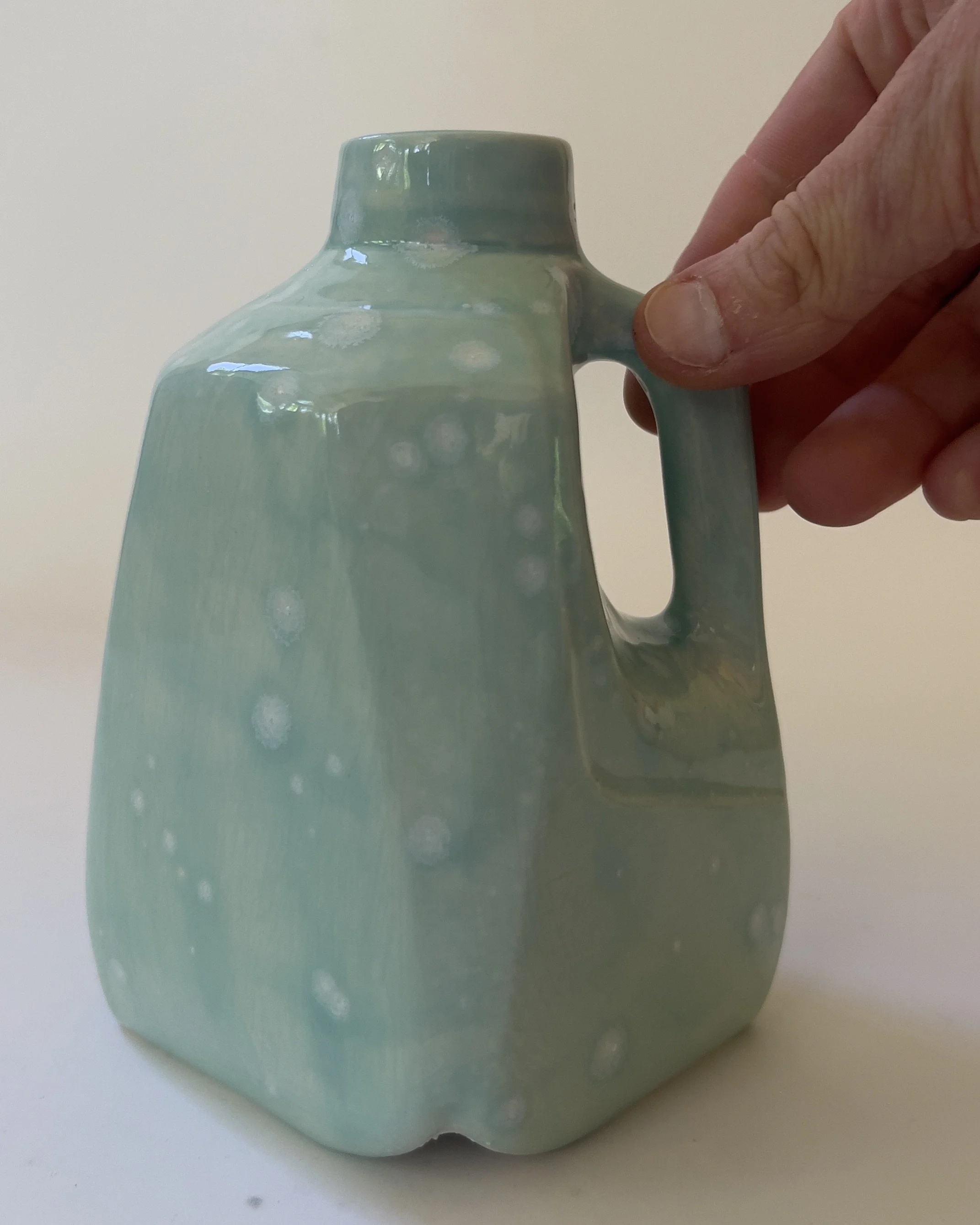 Scale view of small handmade ceramic milk jug sculpture held in hand