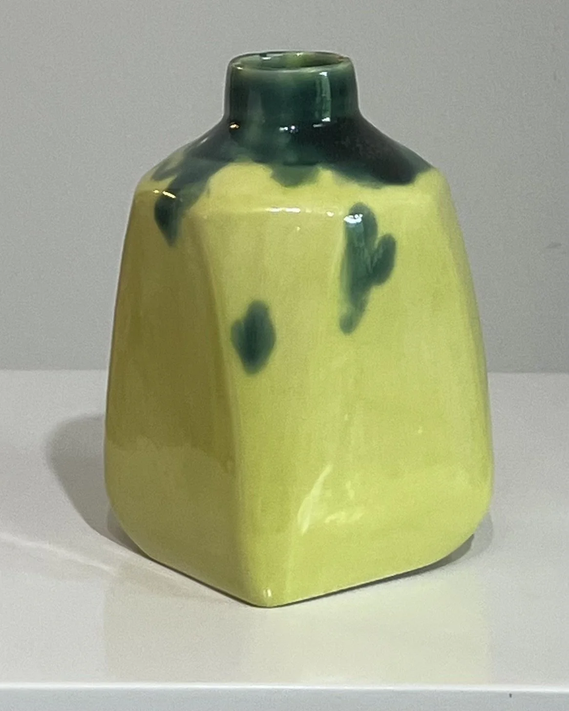 Corner view of a contemporary porcelain milk jug featuring layered lime green and dark green glazes.