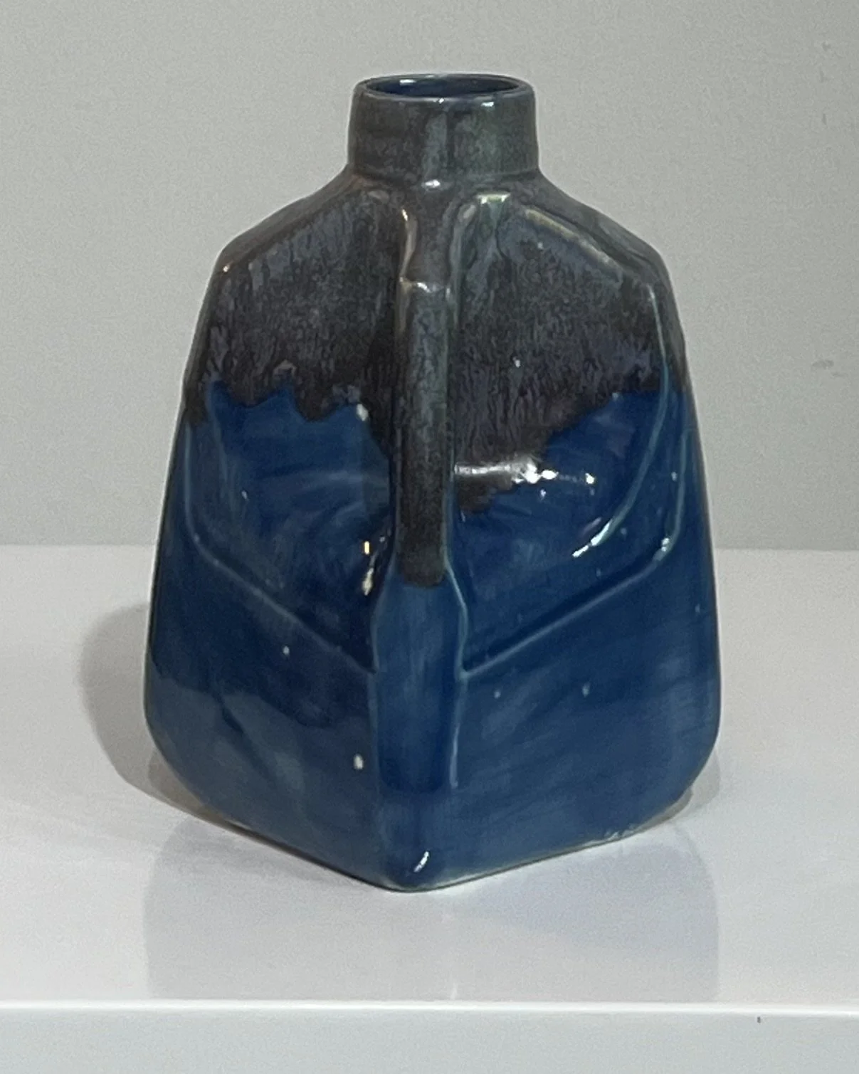 Corner view of a contemporary porcelain milk jug with flowing cobalt blue and smoky gray glazes.
