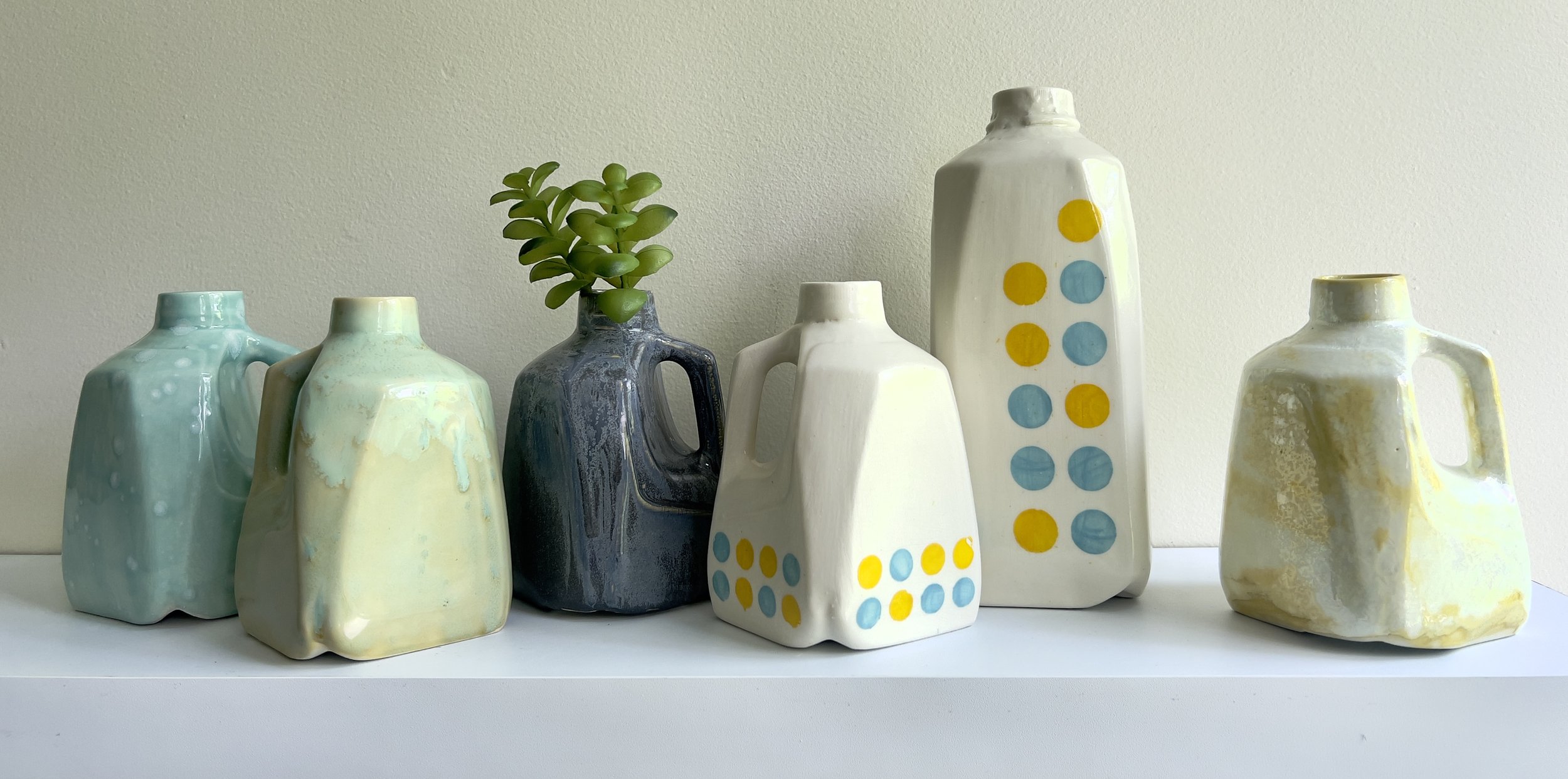 Collection of handmade porcelain milk jug and carton vessels by Alissa Van Atta in blue, cream, yellow, and polka dot glazes