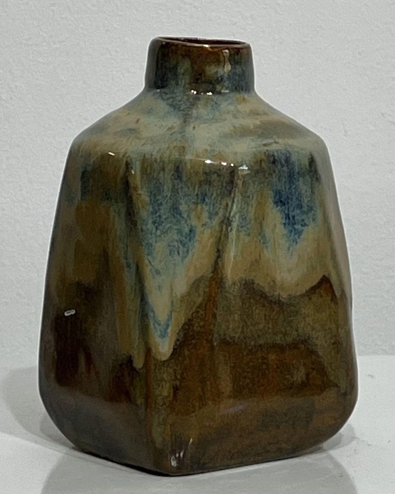 Alternate view of small ceramic milk jug showing flowing blue-green glaze and bronze-brown base