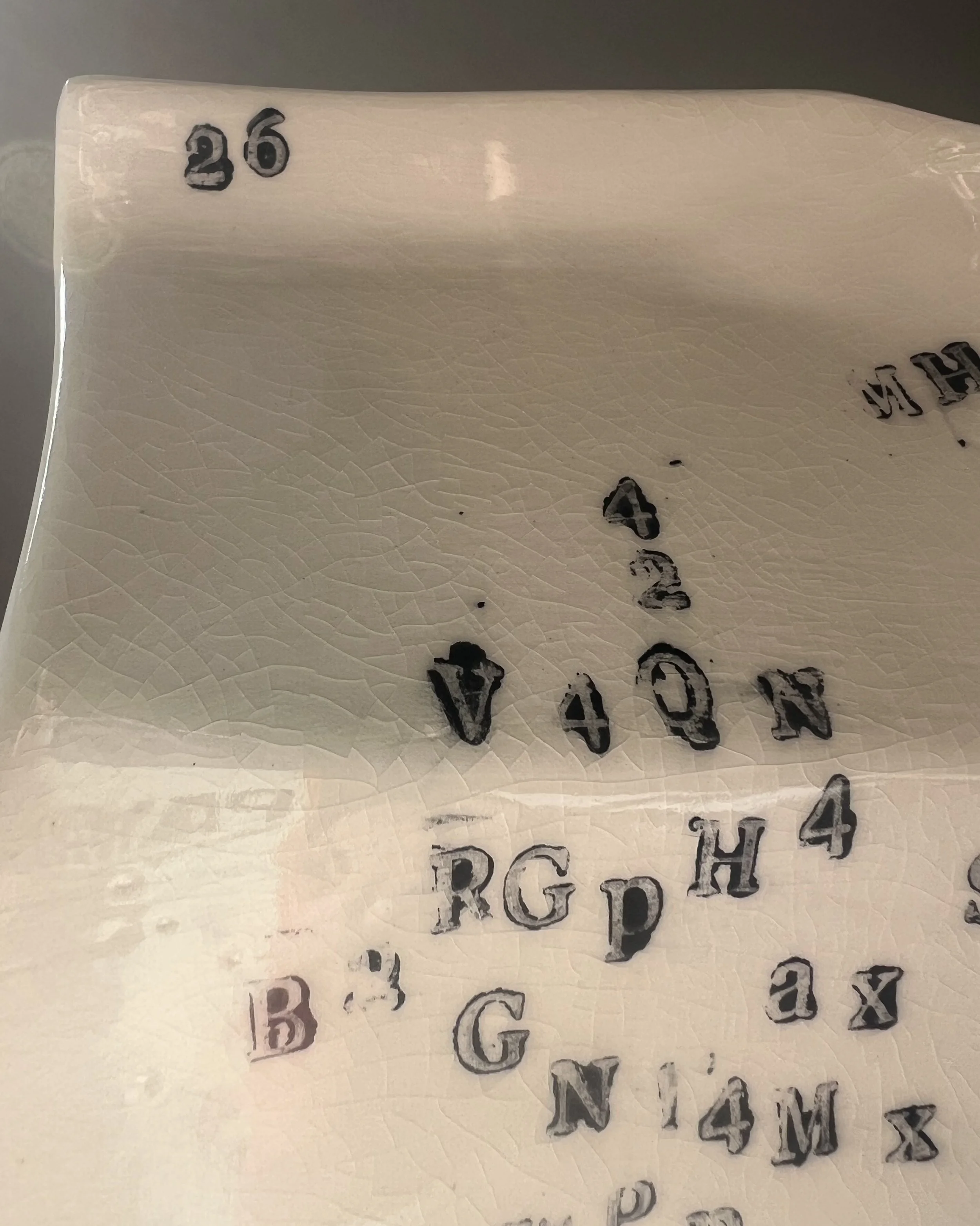Close-up of impressed black typography on the surface of a handbuilt porcelain milk carton.