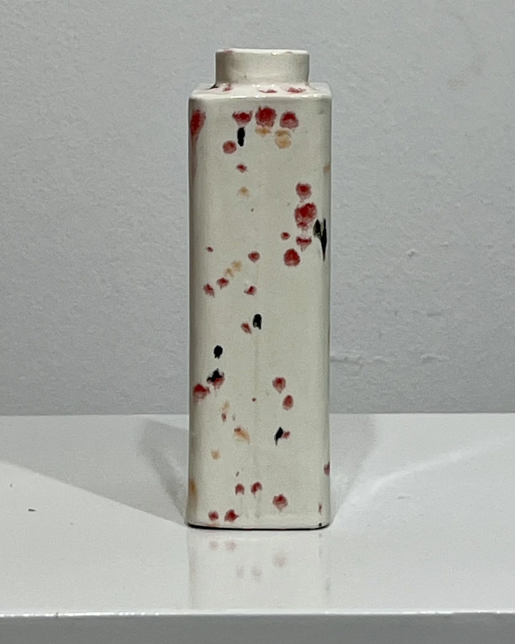 Opposite side view of Poppy Fields porcelain carton vase C26.6 with varied red, peach, and black speckled glaze details.