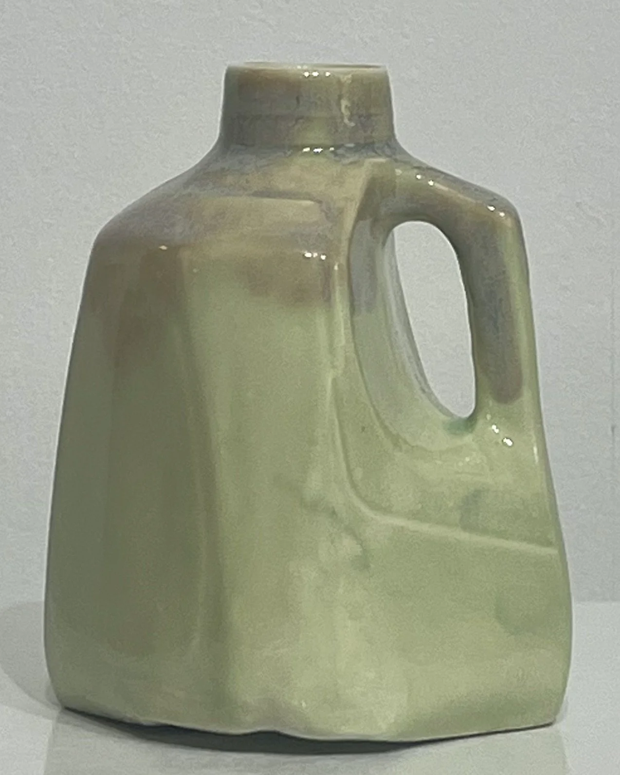 Front view of a handmade pistachio-green porcelain milk jug vase with a glossy ceramic glaze.