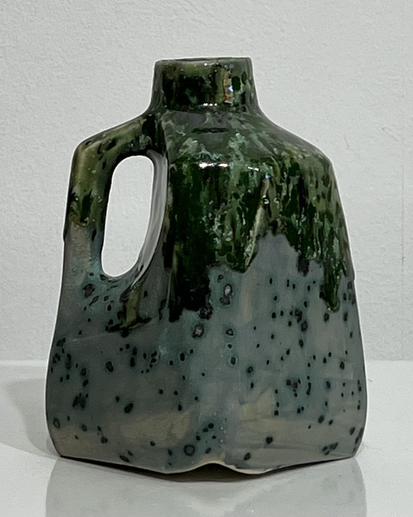 Back view of one-of-a-kind porcelain milk jug showing mottled green glaze variations