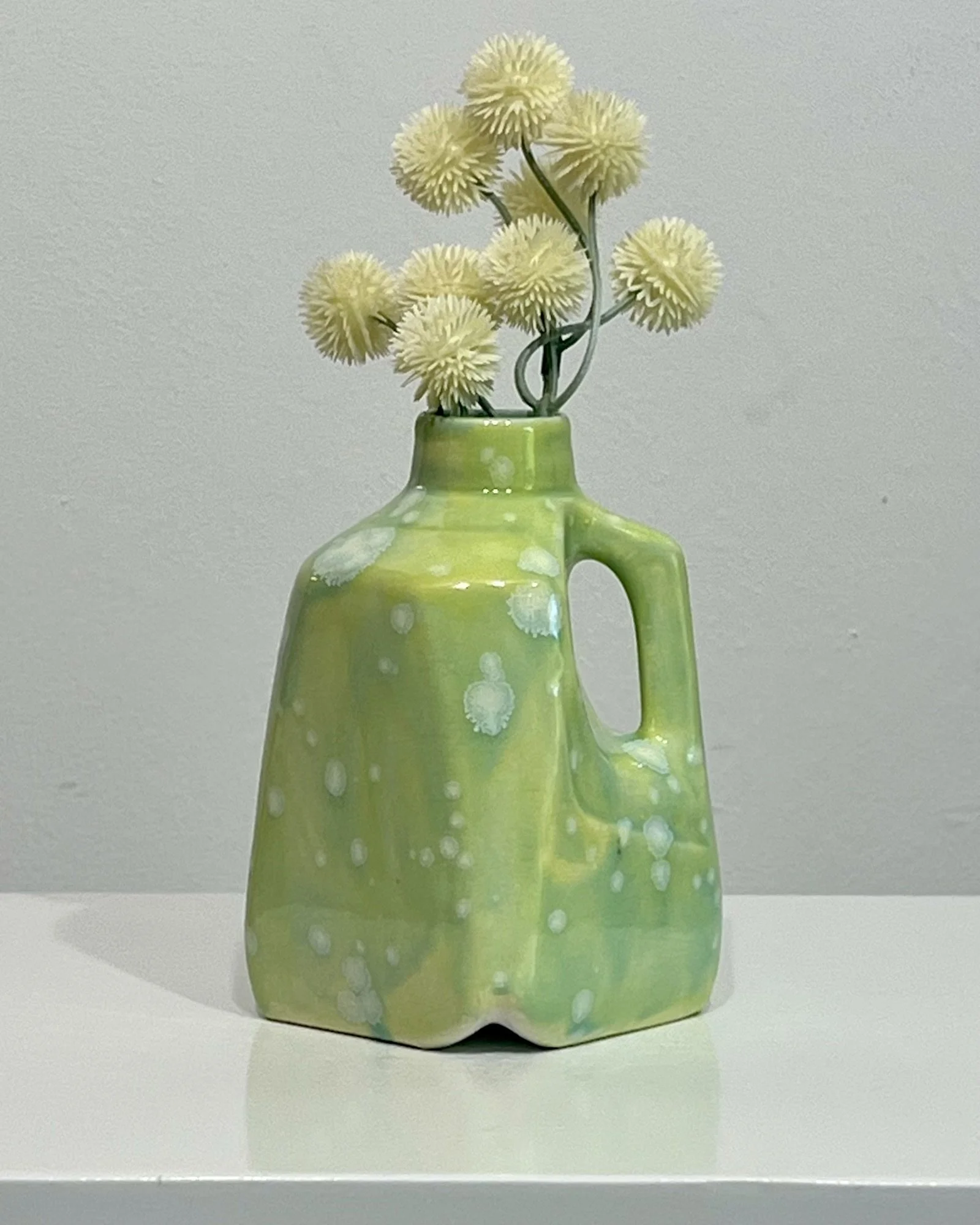 Handmade porcelain milk jug vase glazed in Celadon Bloom over Pear with pale green flowers.