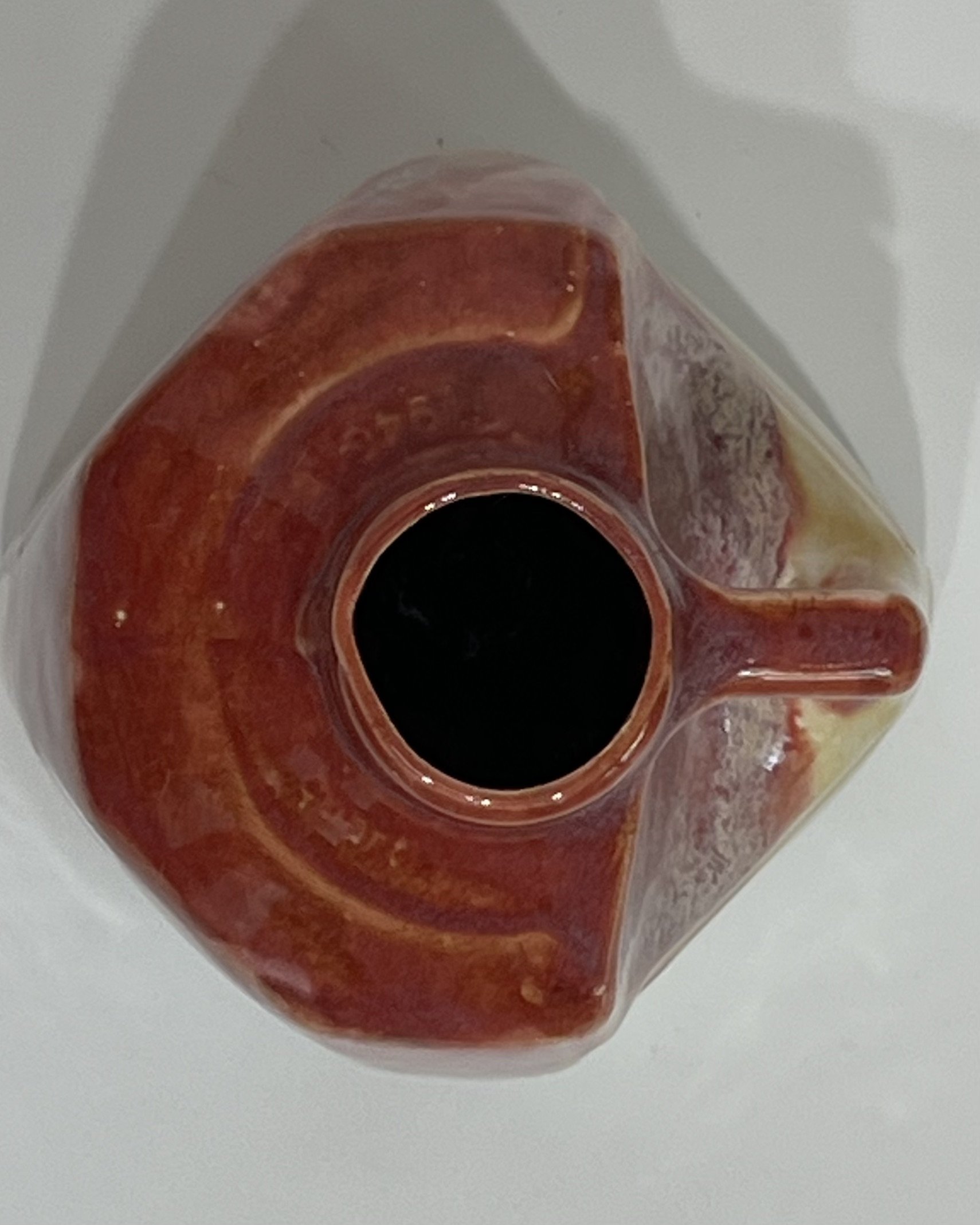 Overhead view of a porcelain milk jug showing its circular opening, plum-colored glazed rim, and handle