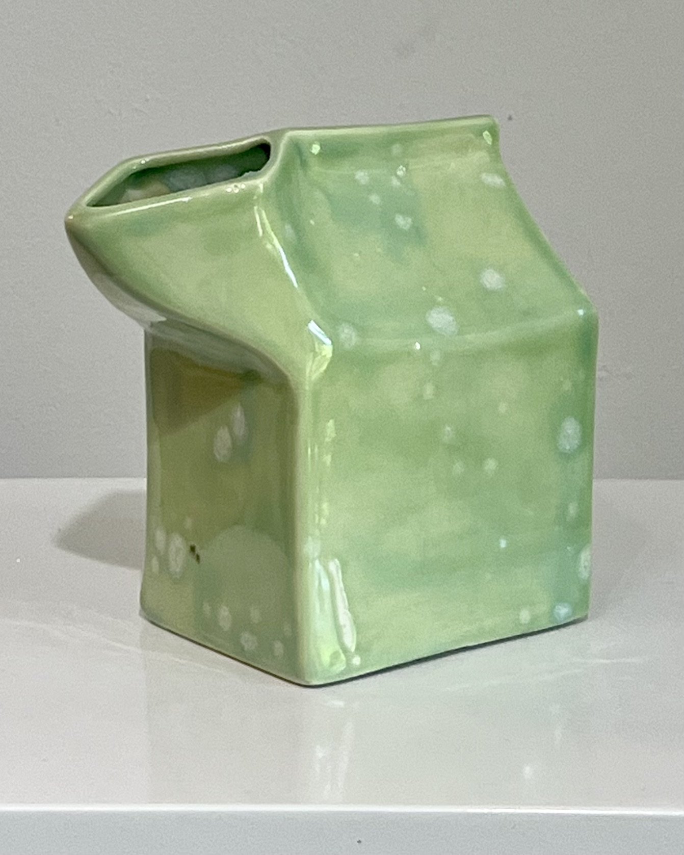 Three-quarter view highlighting crystalline glaze movement across the porcelain milk carton.