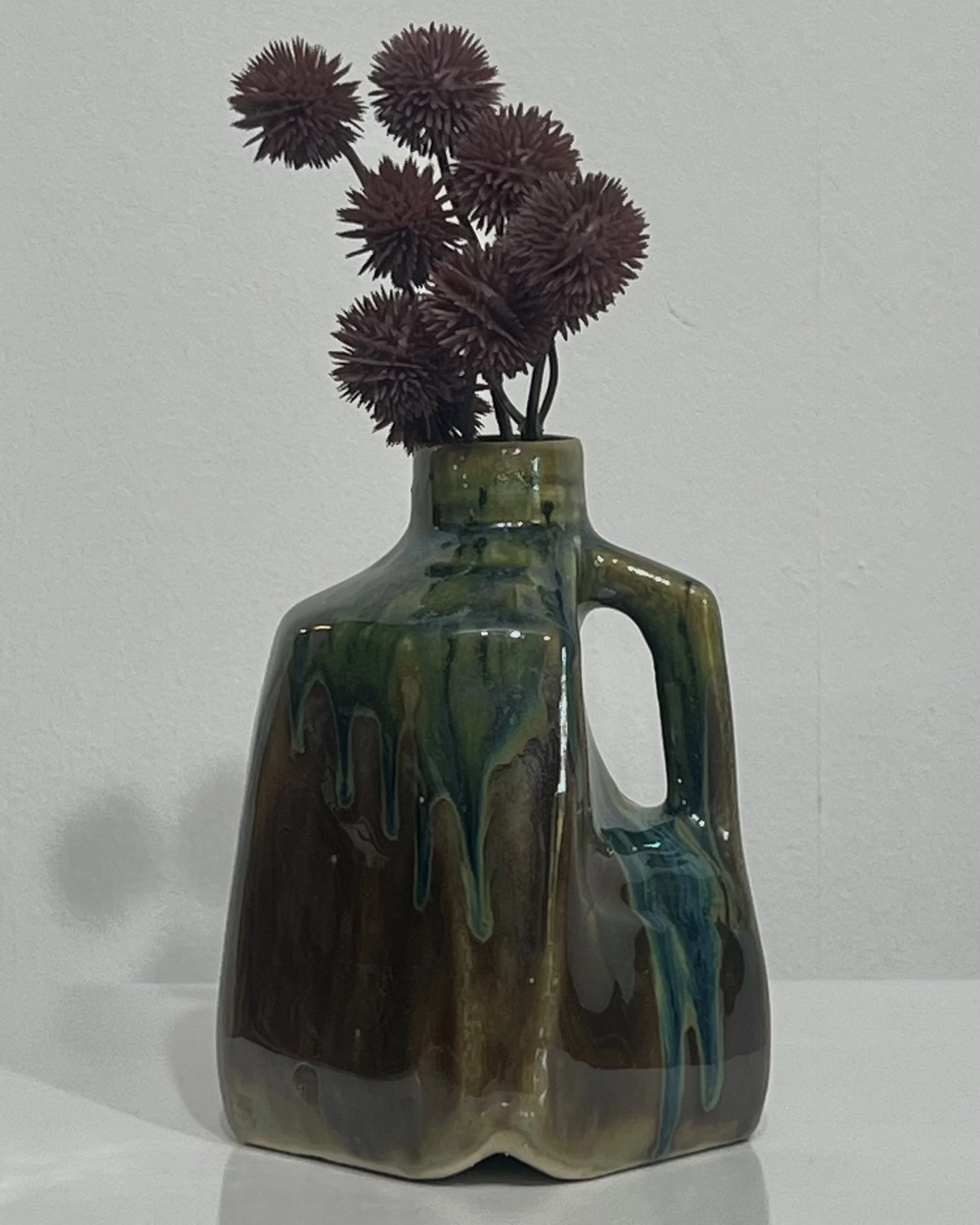 Handmade porcelain milk jug vase by Alissa Van Atta with layered Seaweed and Lime Shower glazes, featuring deep green, olive, and warm earthy tones.