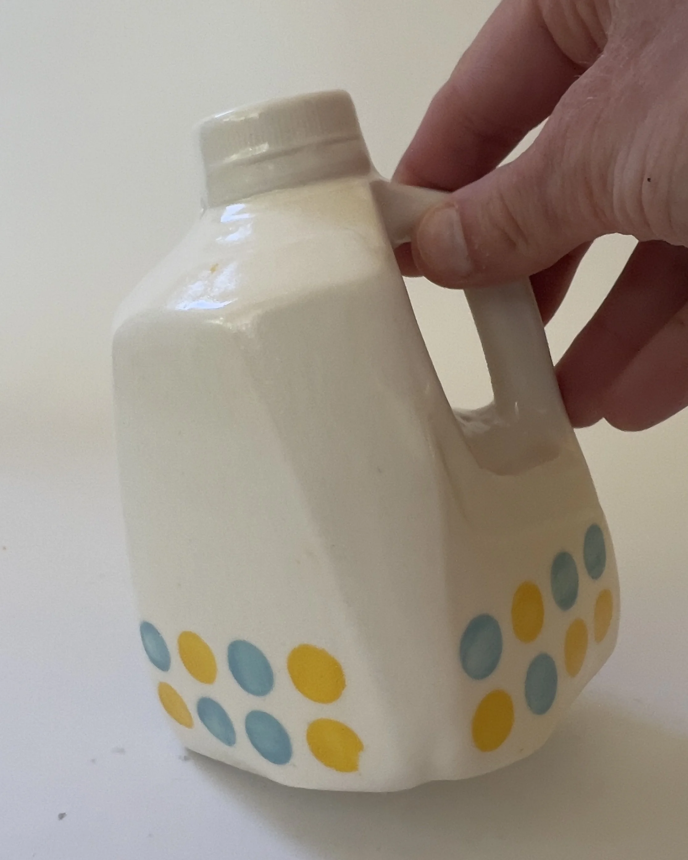 Small handbuilt ceramic jug sculpture shown in hand for scale