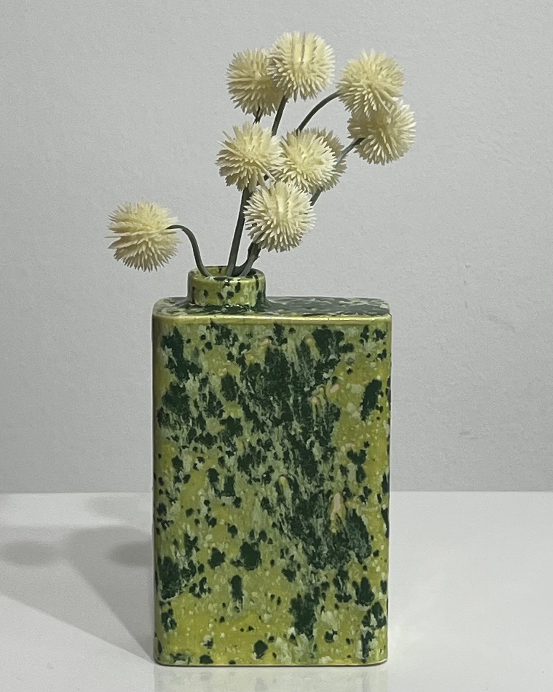 Handmade Lime Shower porcelain carton by Alissa Van Atta with bright chartreuse and dark green speckled glaze, styled with small white flowers.