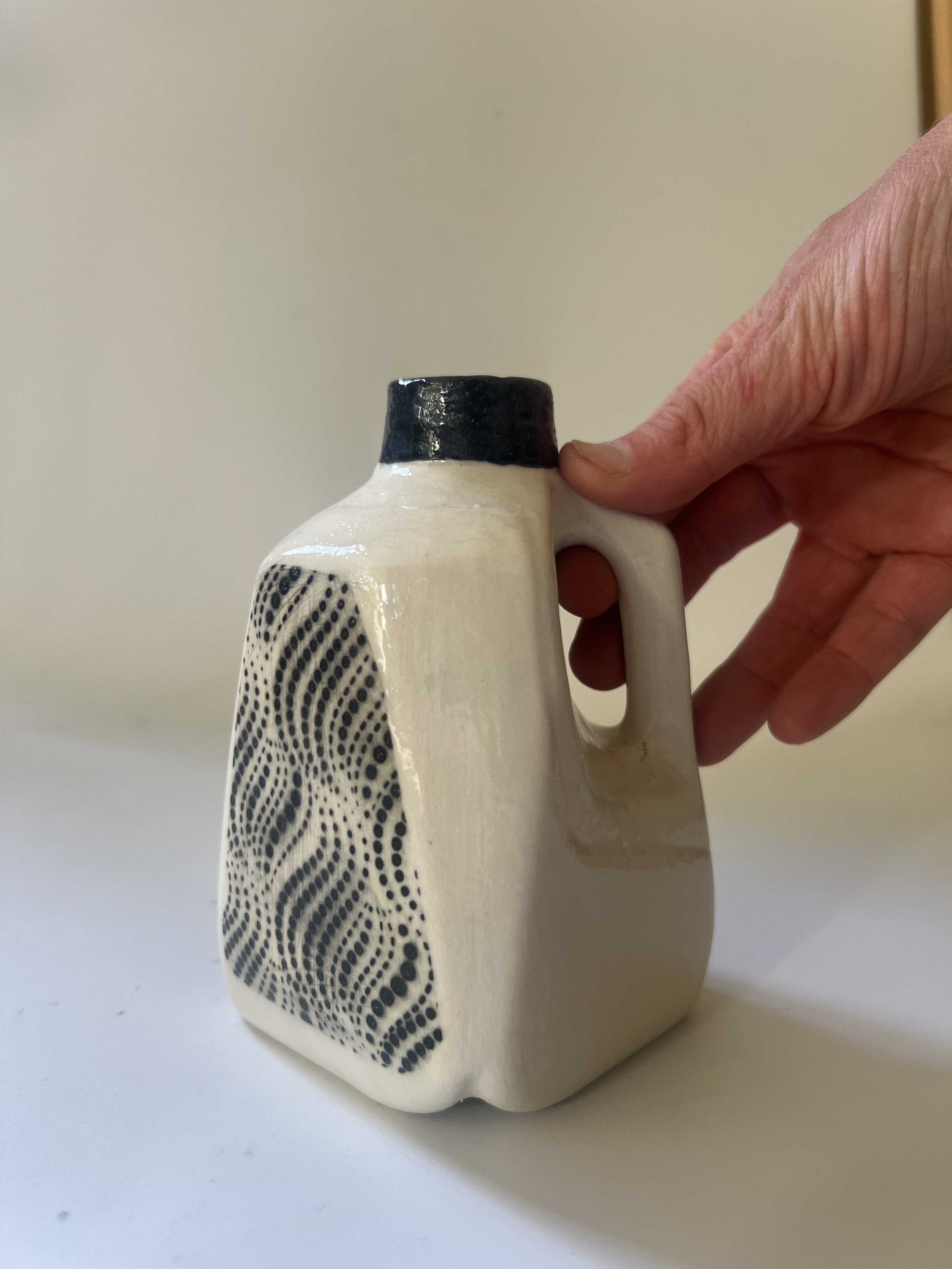 Small handmade porcelain milk jug vase shown in hand for scale.