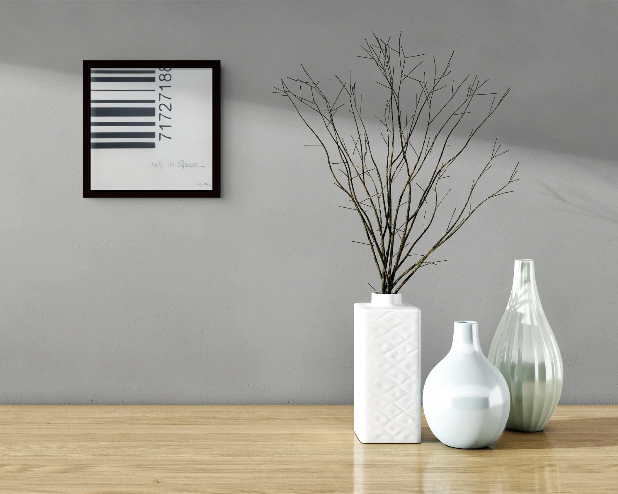 Not in Stock, small framed black-and-white conceptual barcode artwork by Alissa Van Atta, displayed on a gray wall above a wooden console with white ceramic vases.