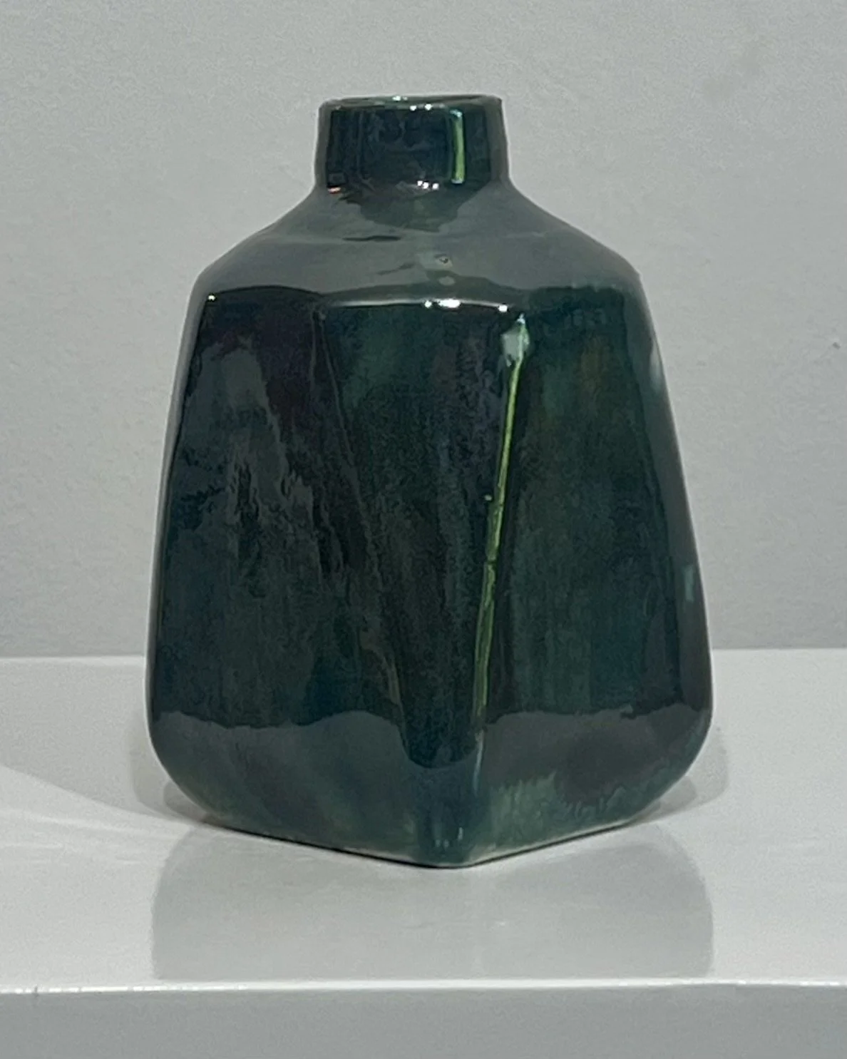Back view of porcelain milk jug vase with flowing Vintage Gold over Rainforest glaze in deep green and bronze tones.