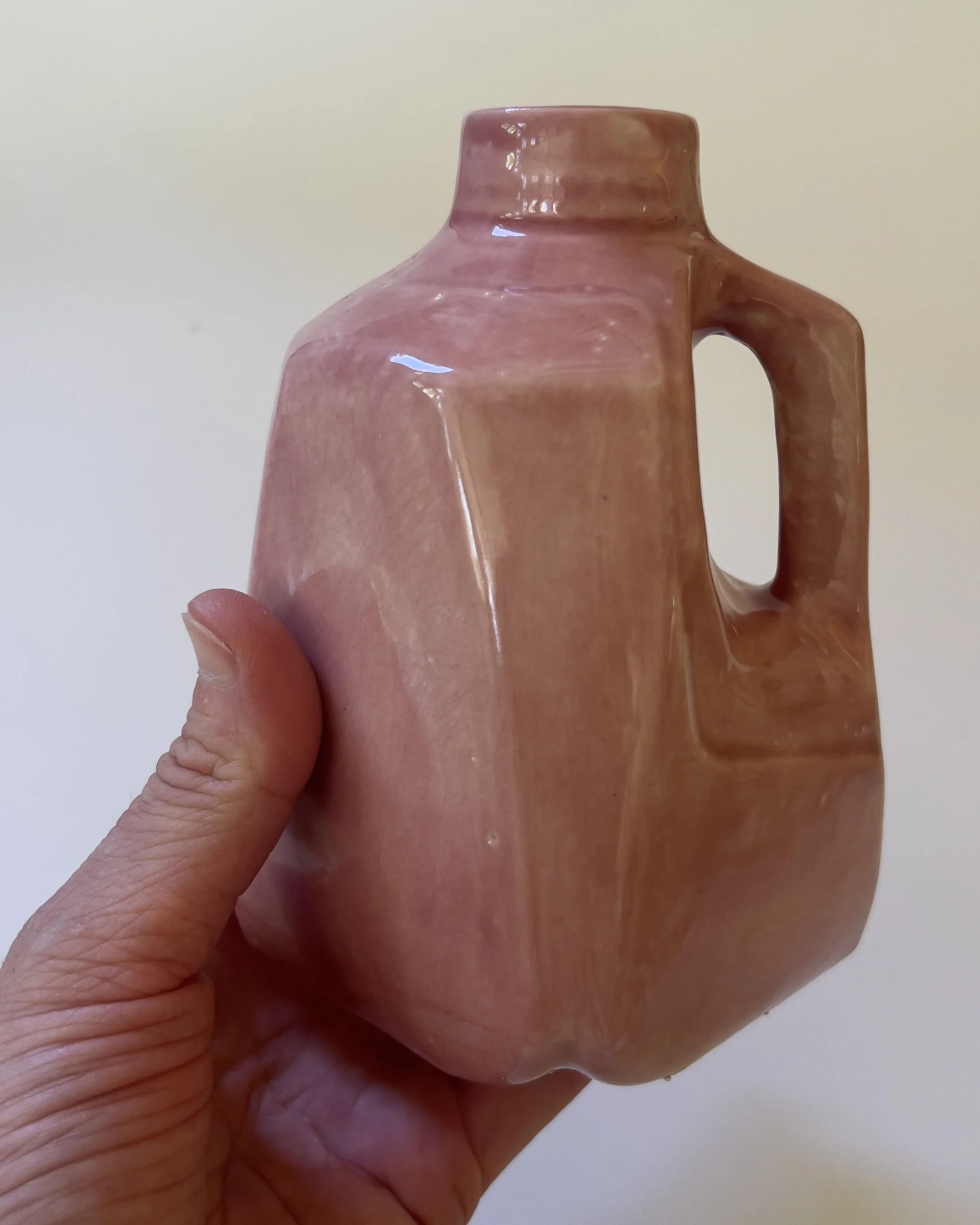 Small ceramic milk jug sculpture shown in hand for scale