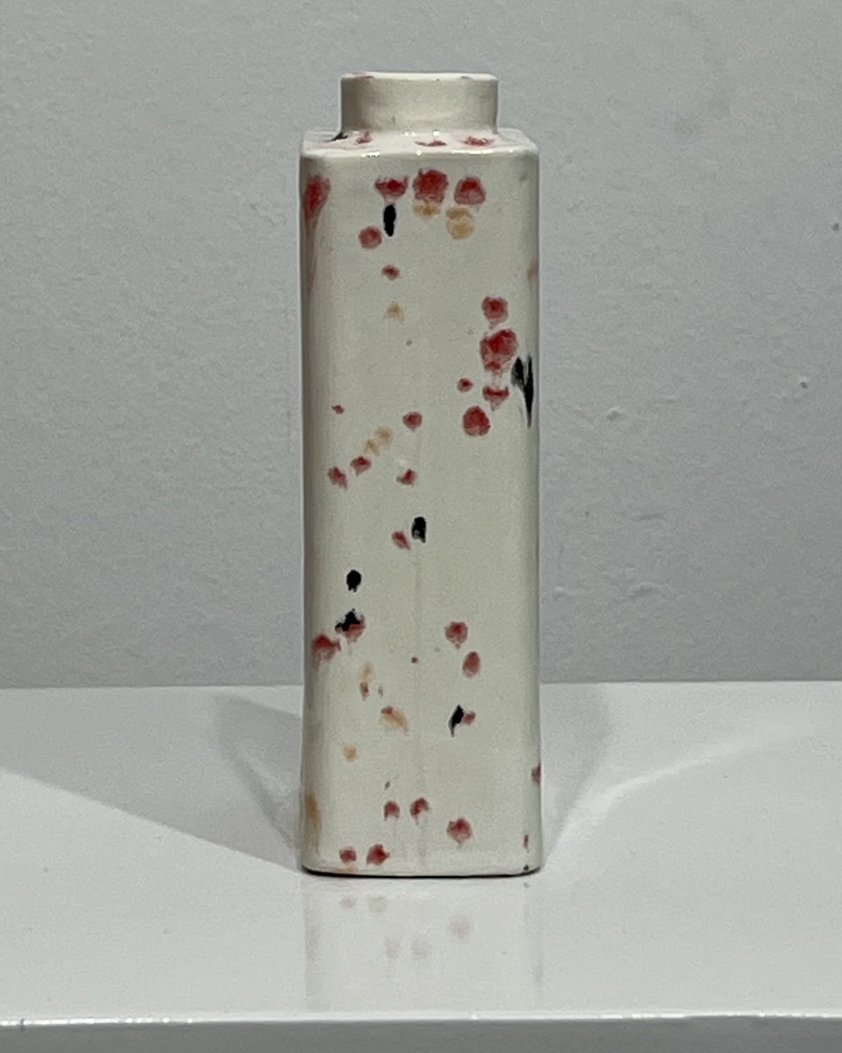 Side view of Poppy Fields porcelain carton vase C26.6 showing cream glaze with red, peach, and black speckled pattern.