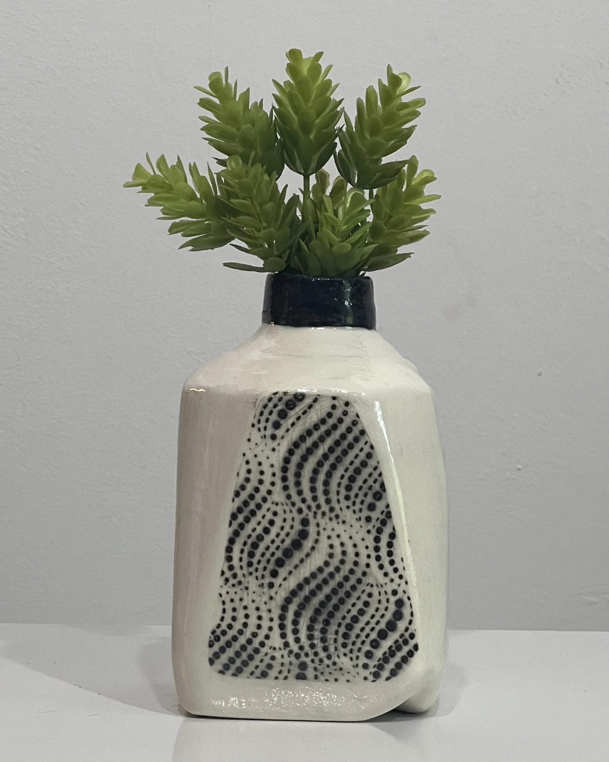 Contemporary ceramic milk jug with abstract black dot pattern and glossy cream glaze.