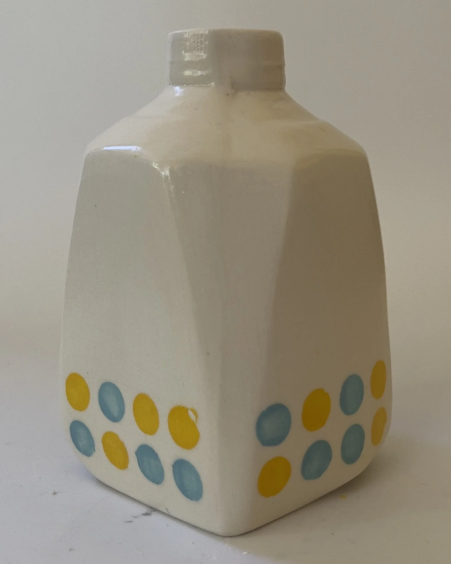 Back angle of white ceramic jug sculpture with blue and yellow dot pattern