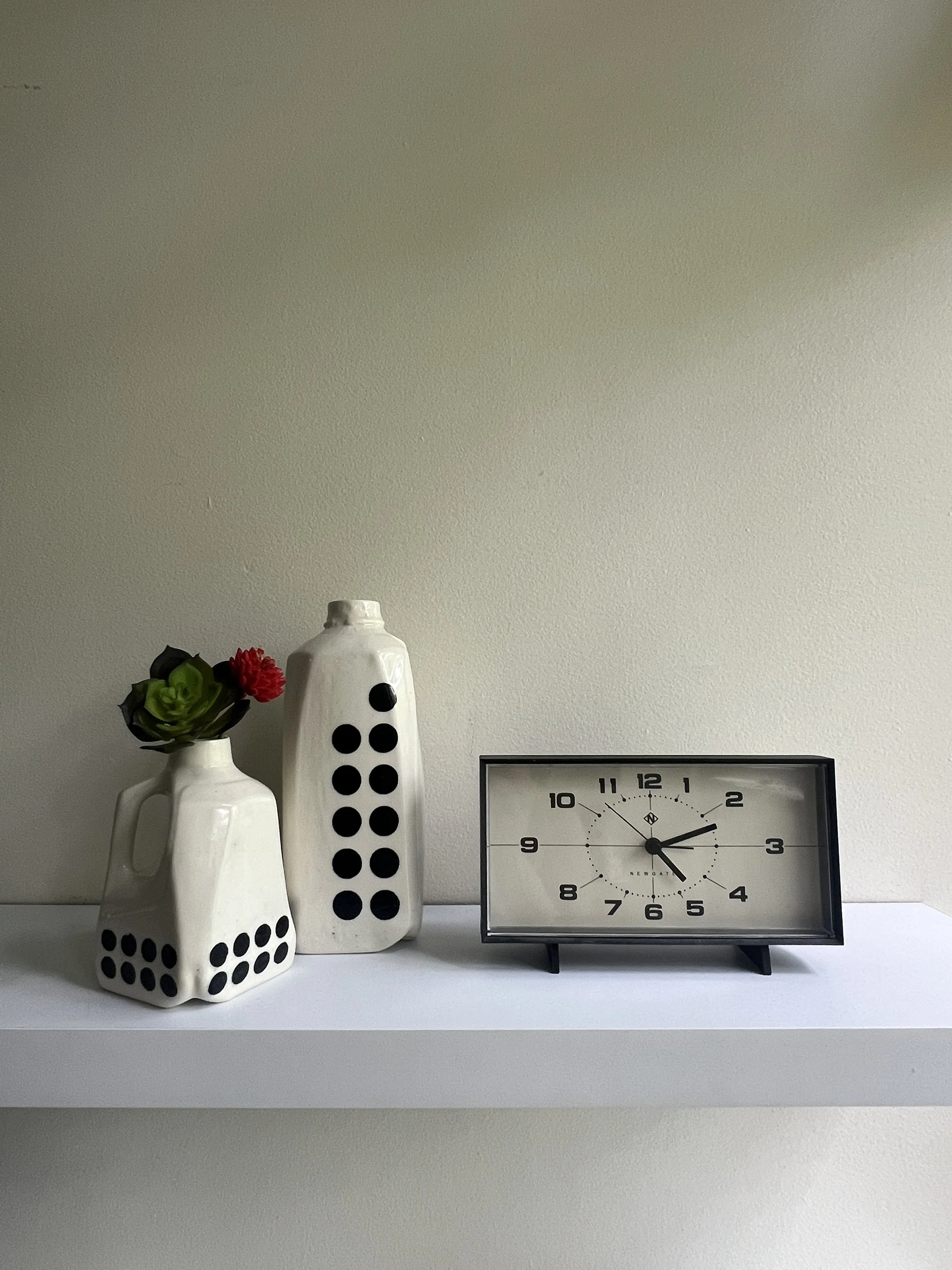 Styled shelf display featuring handmade ceramic jug vases and modern clock
