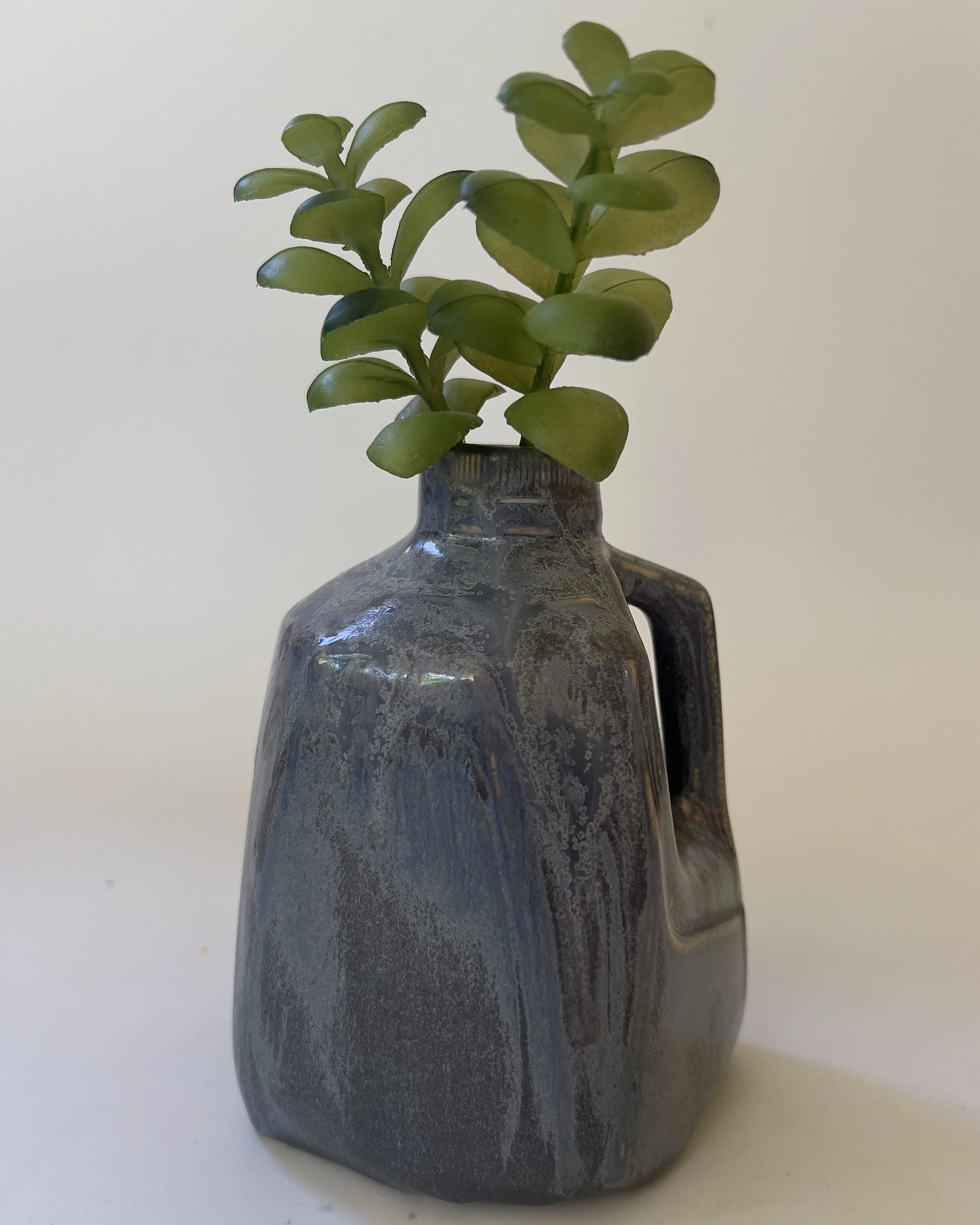 Sculptural handmade ceramic jug vase styled with green stems