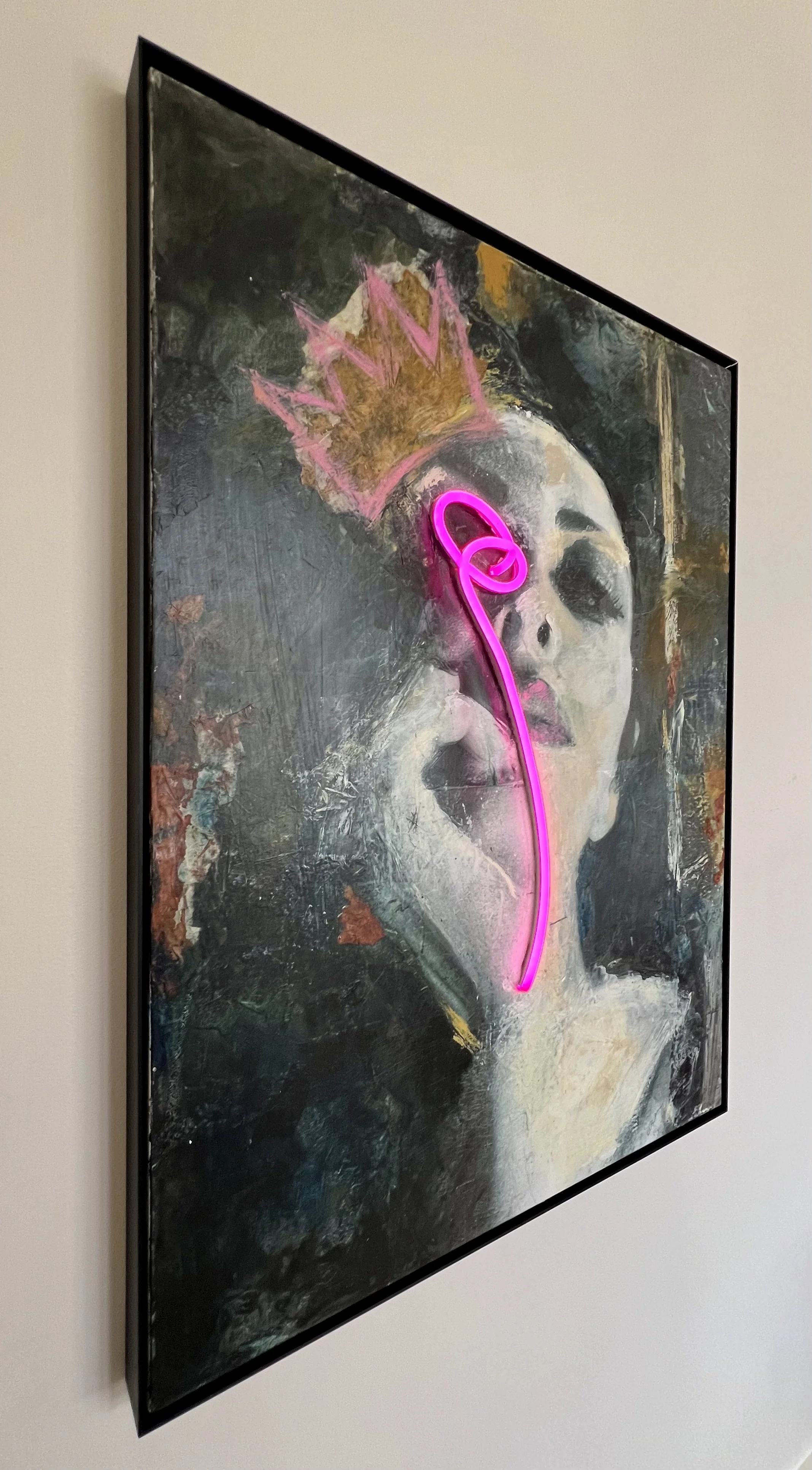 Angled view of Neon Queen by Alissa Van Atta showing the framed original mixed media canvas and dimensional pink neon lighting element.